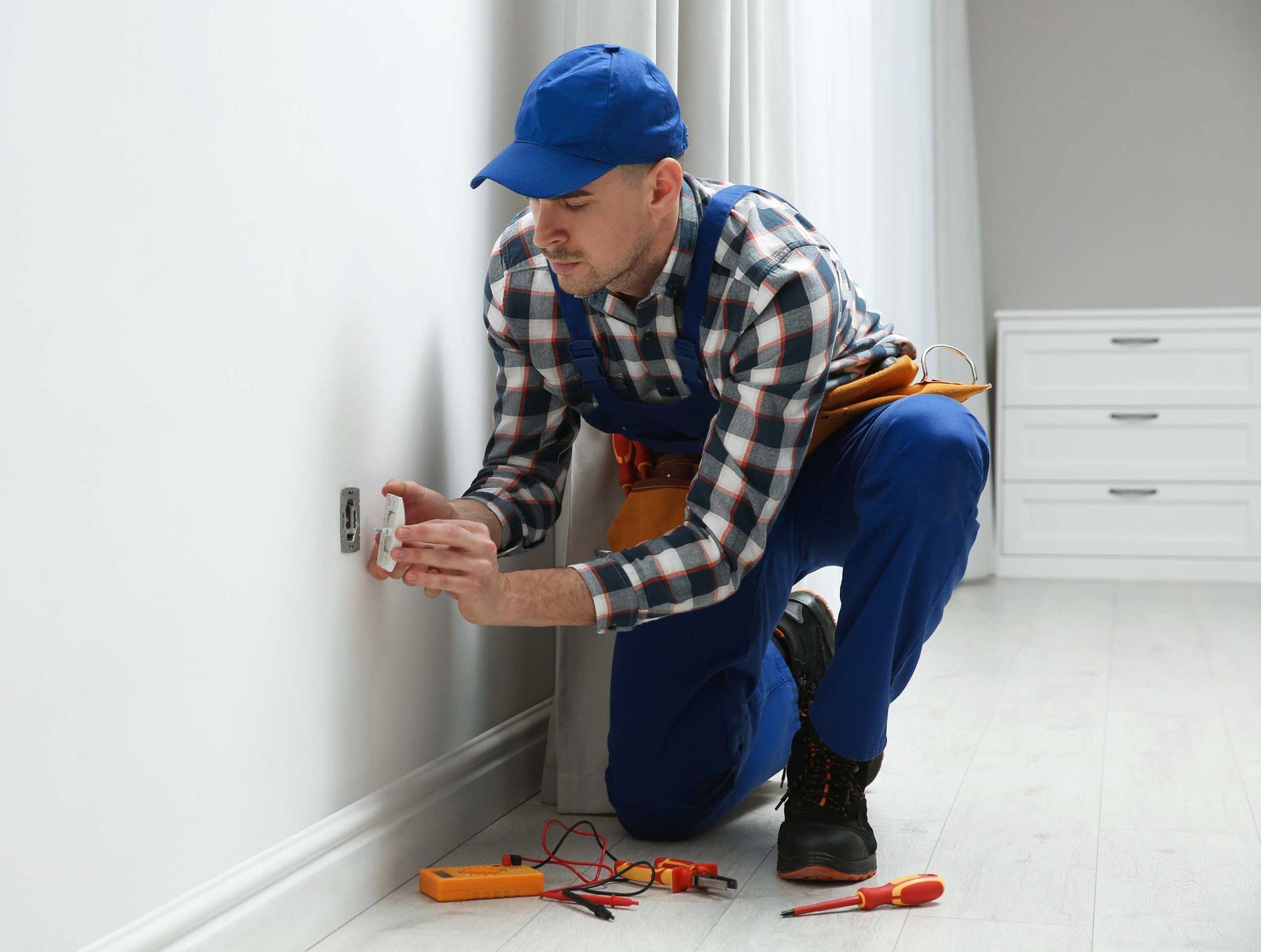 A professional male electrician is repairing a power socket in a room