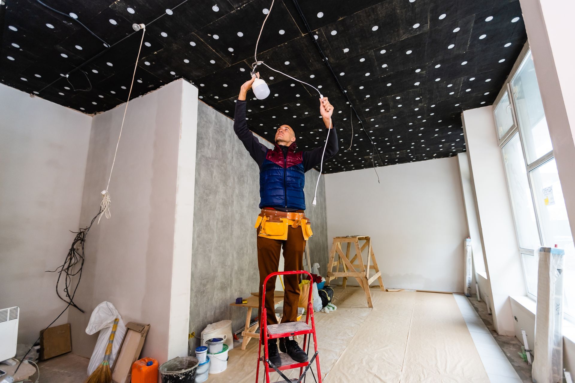 A commercial electrician installing a lamp on the construction site.