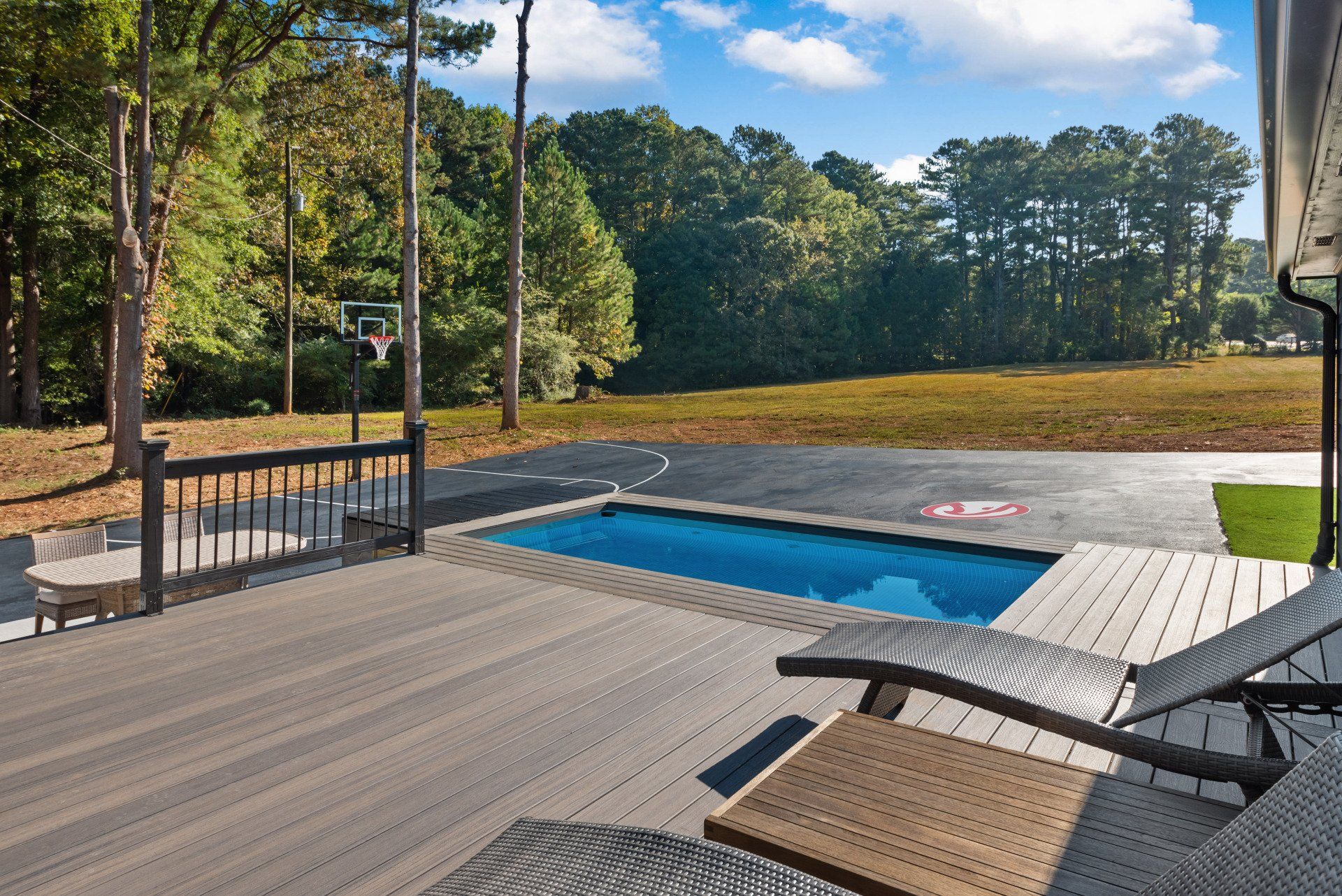 A deck with a swimming pool and a basketball hoop.