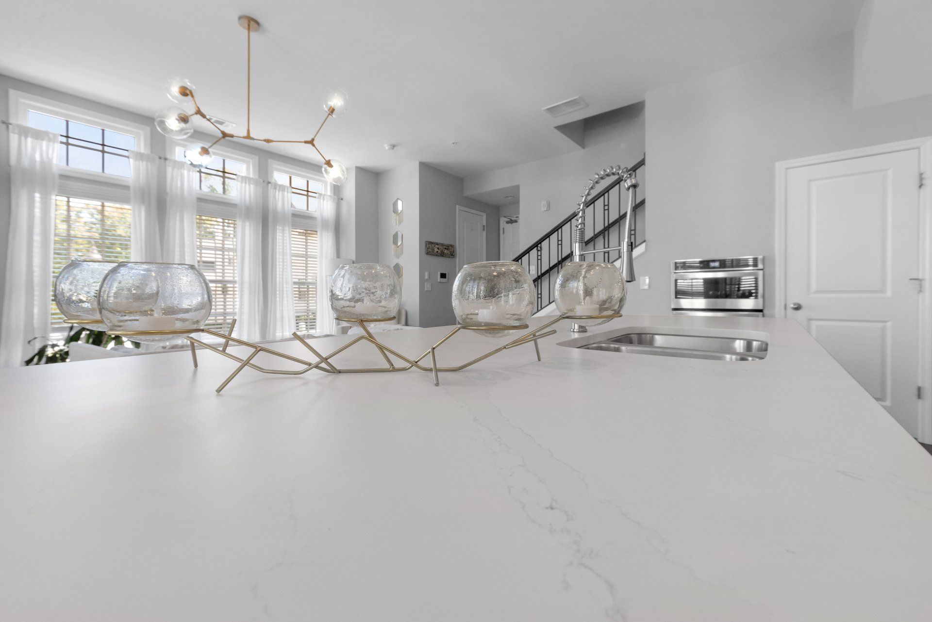 A kitchen with a white counter top and a staircase in the background.
