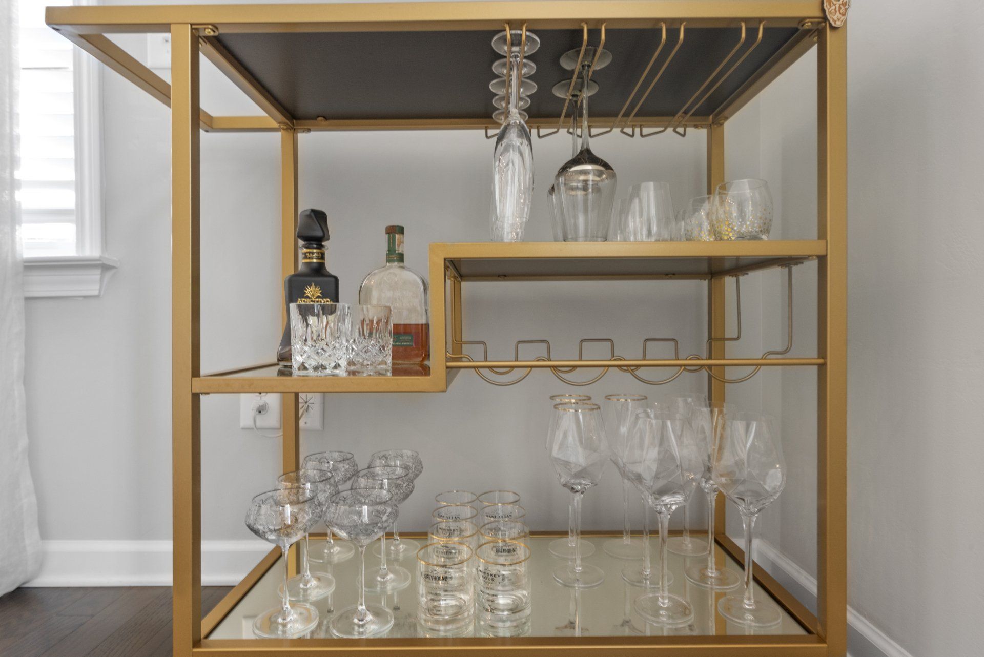 A bar cart with a bottle of whiskey and glasses on it.