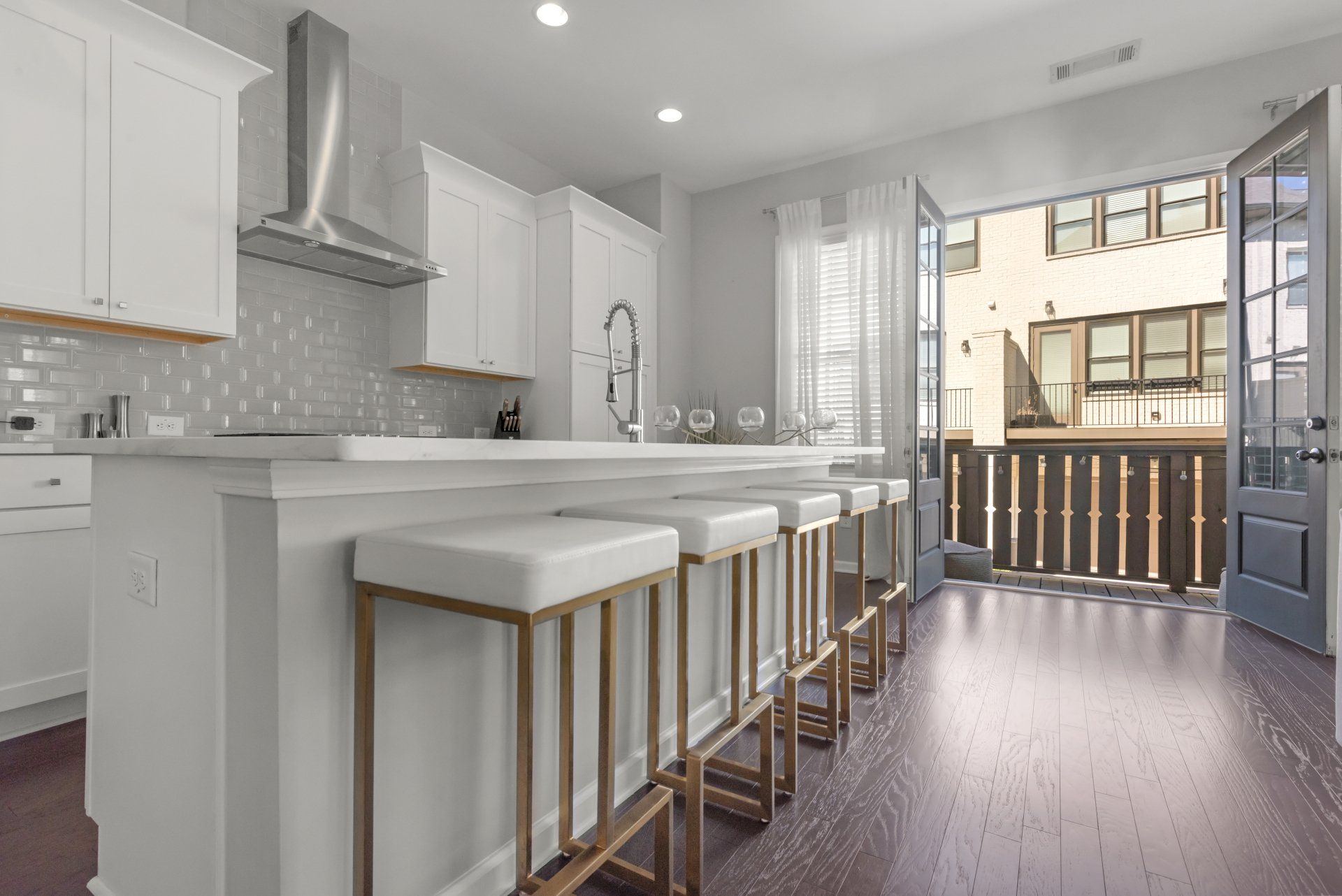 A kitchen with white cabinets and gold bar stools
