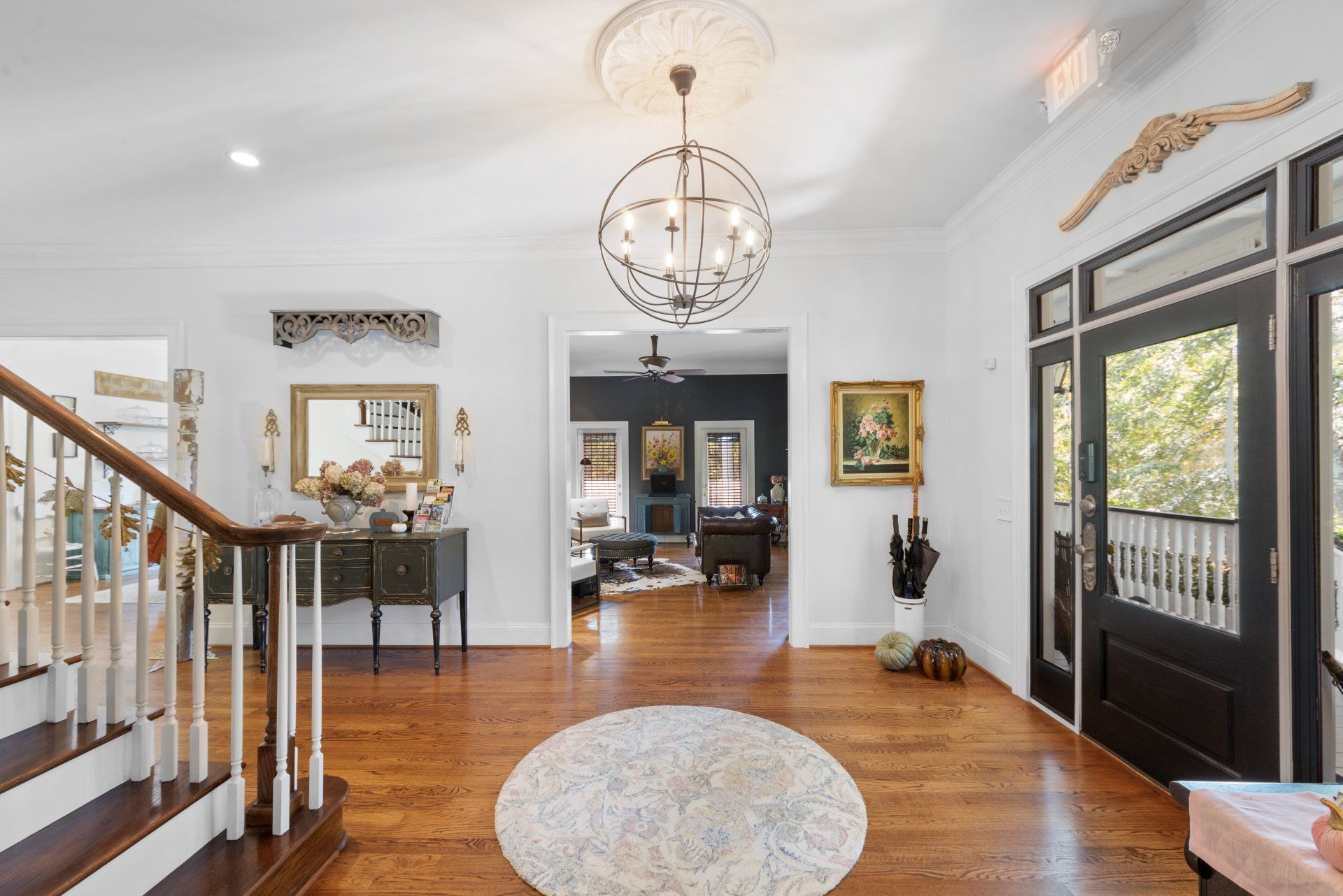 A hallway with stairs and a chandelier hanging from the ceiling