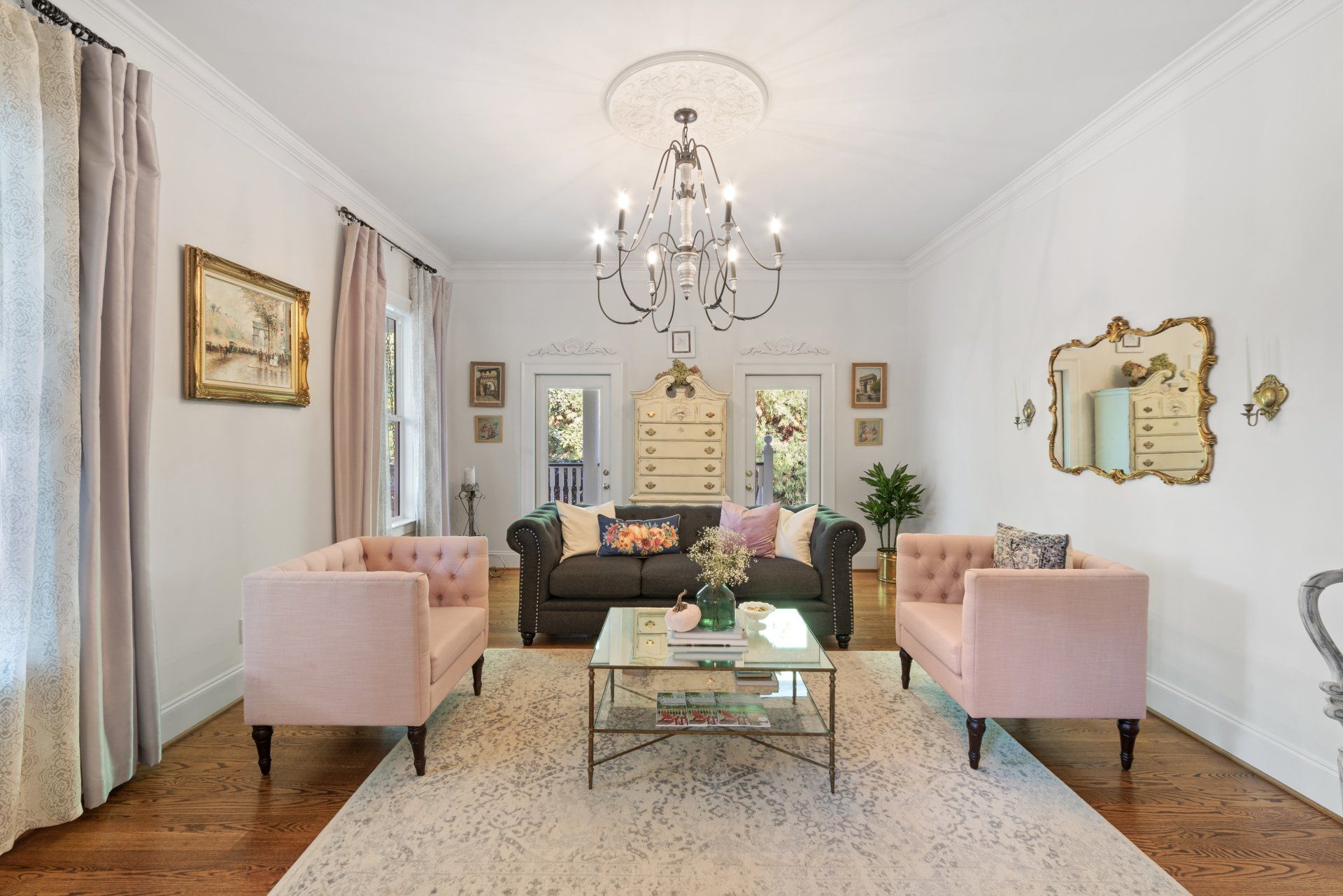 A living room with two pink chairs and a black couch