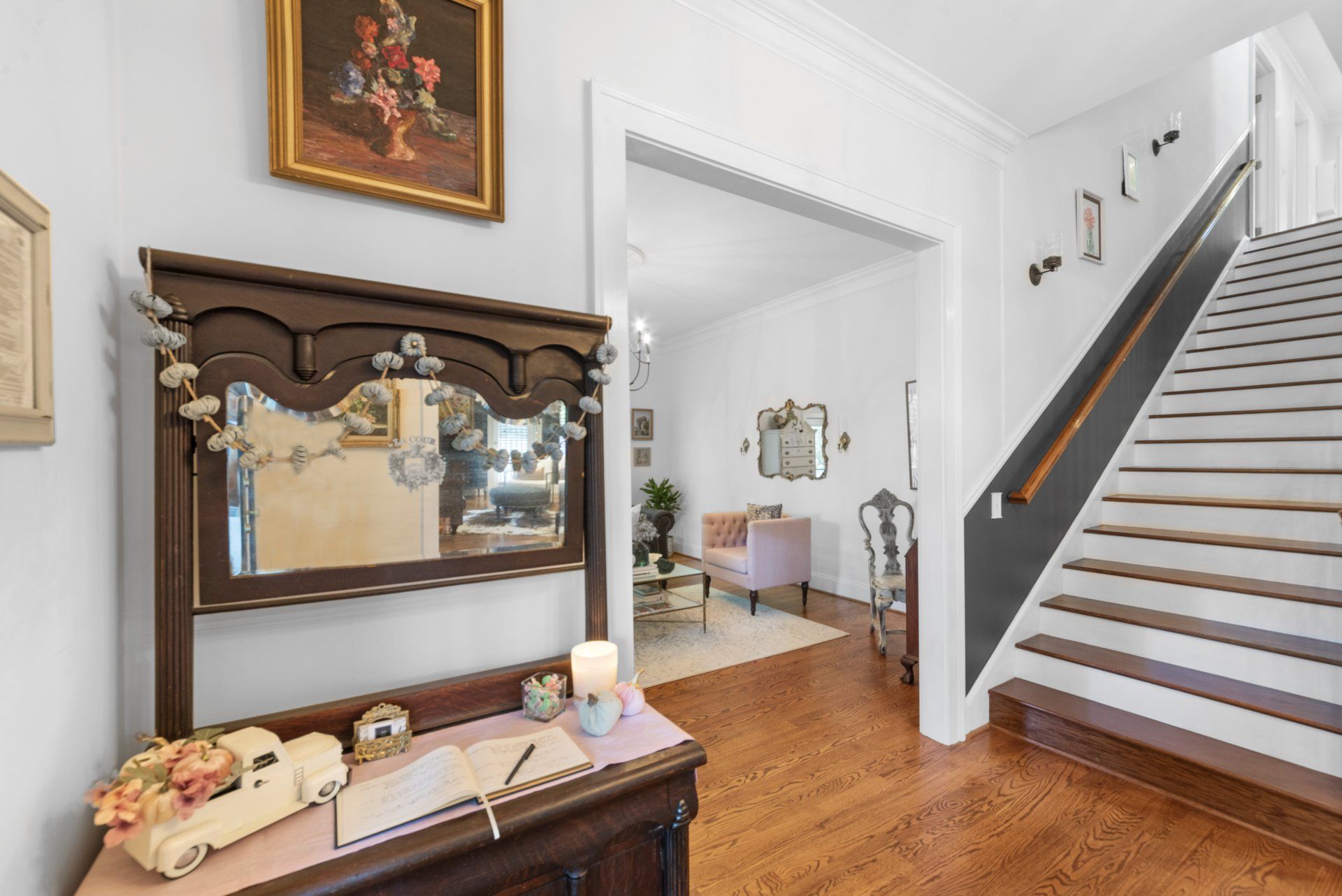 A hallway with stairs and a table with a mirror on it
