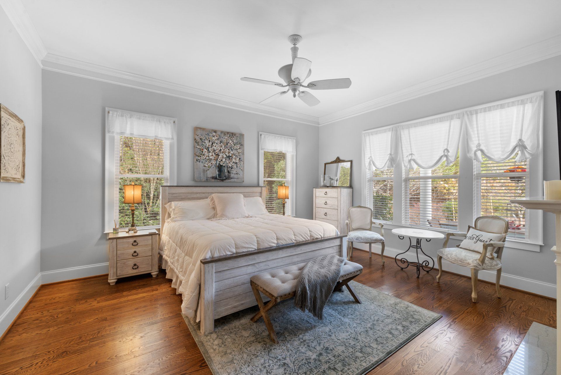 A bedroom with a large bed , a ceiling fan , a bench , and a fireplace.