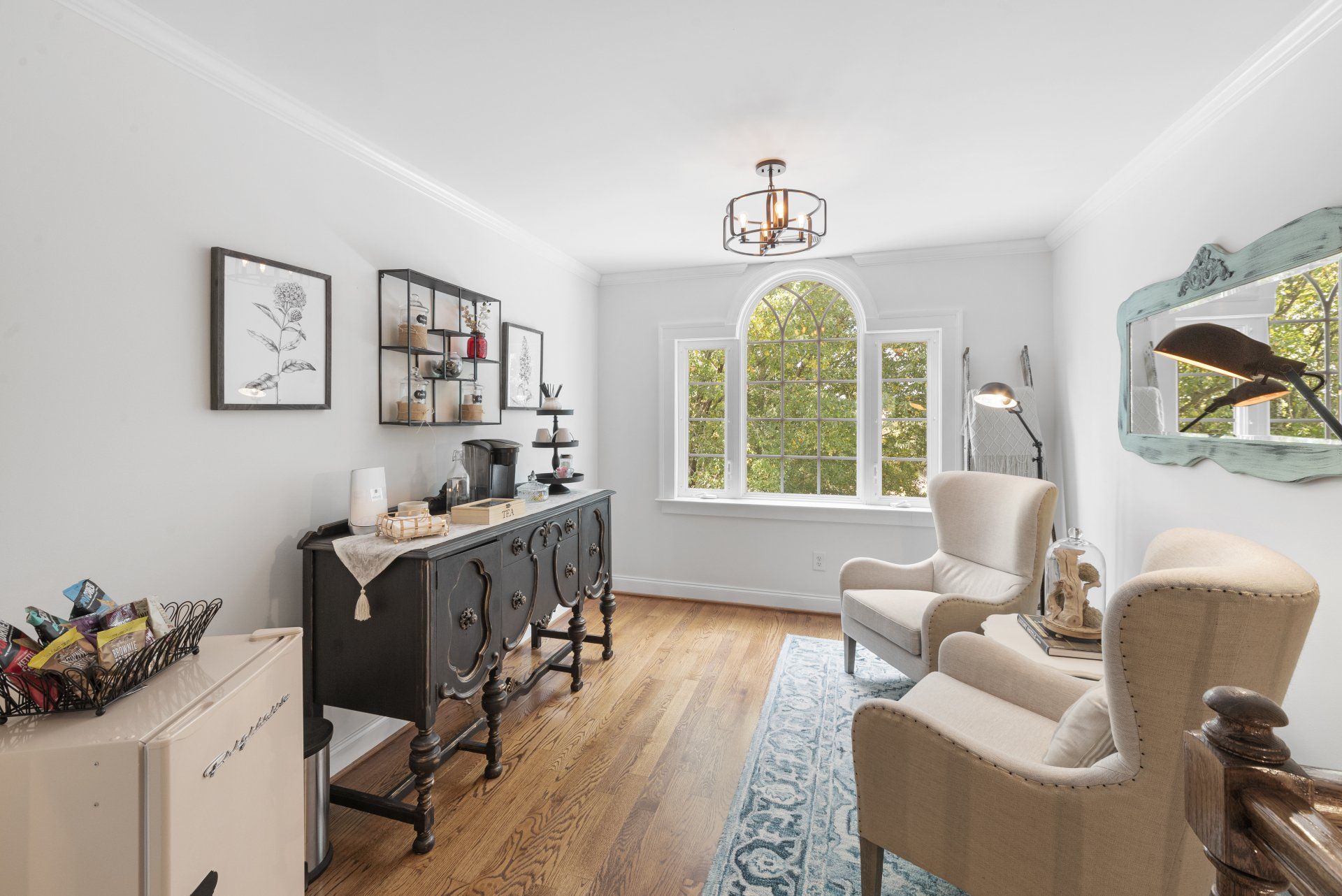 A living room with two chairs , a dresser and a mirror.