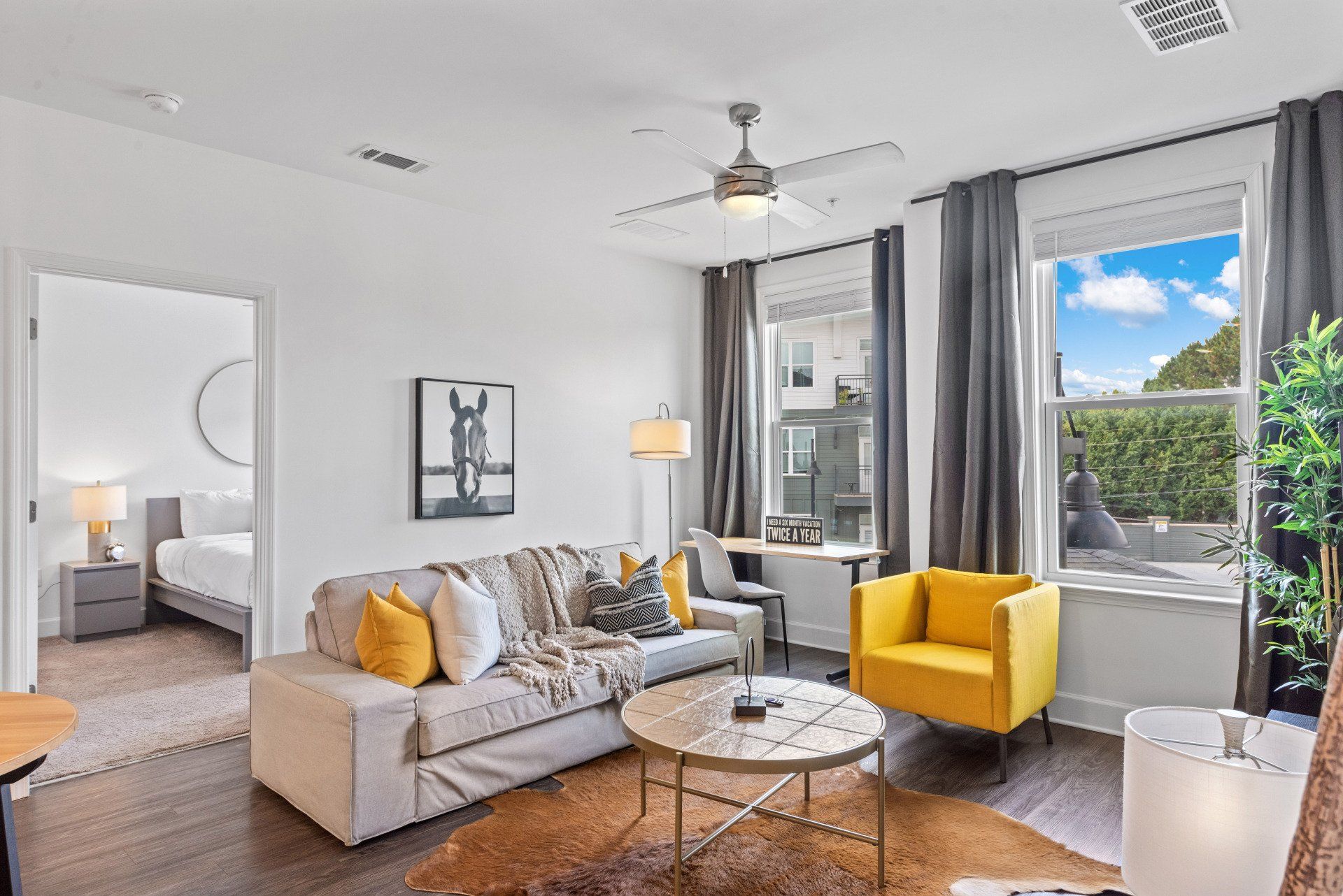 A living room with a couch , chair , coffee table and ceiling fan.