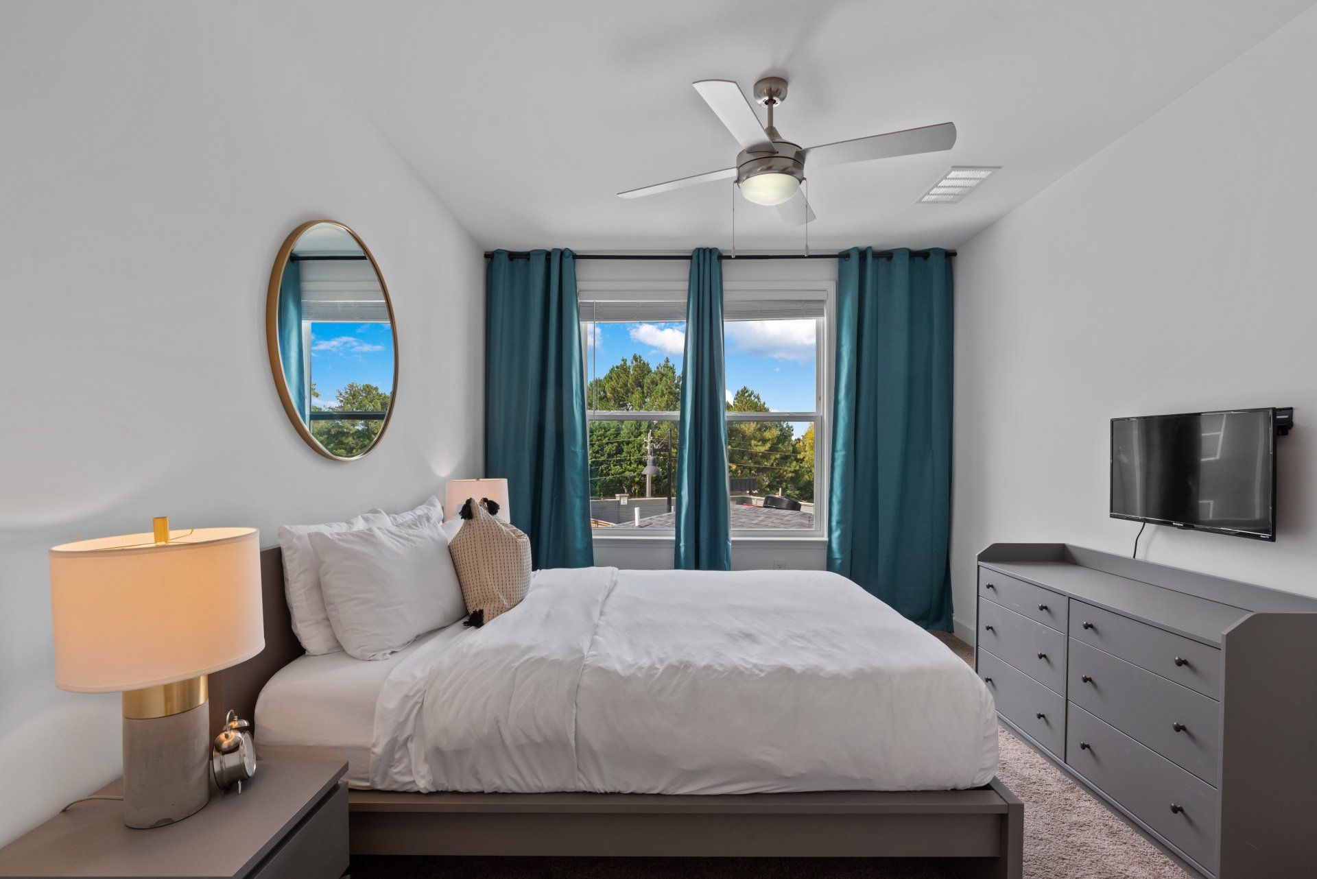 A bedroom with a large bed and a ceiling fan