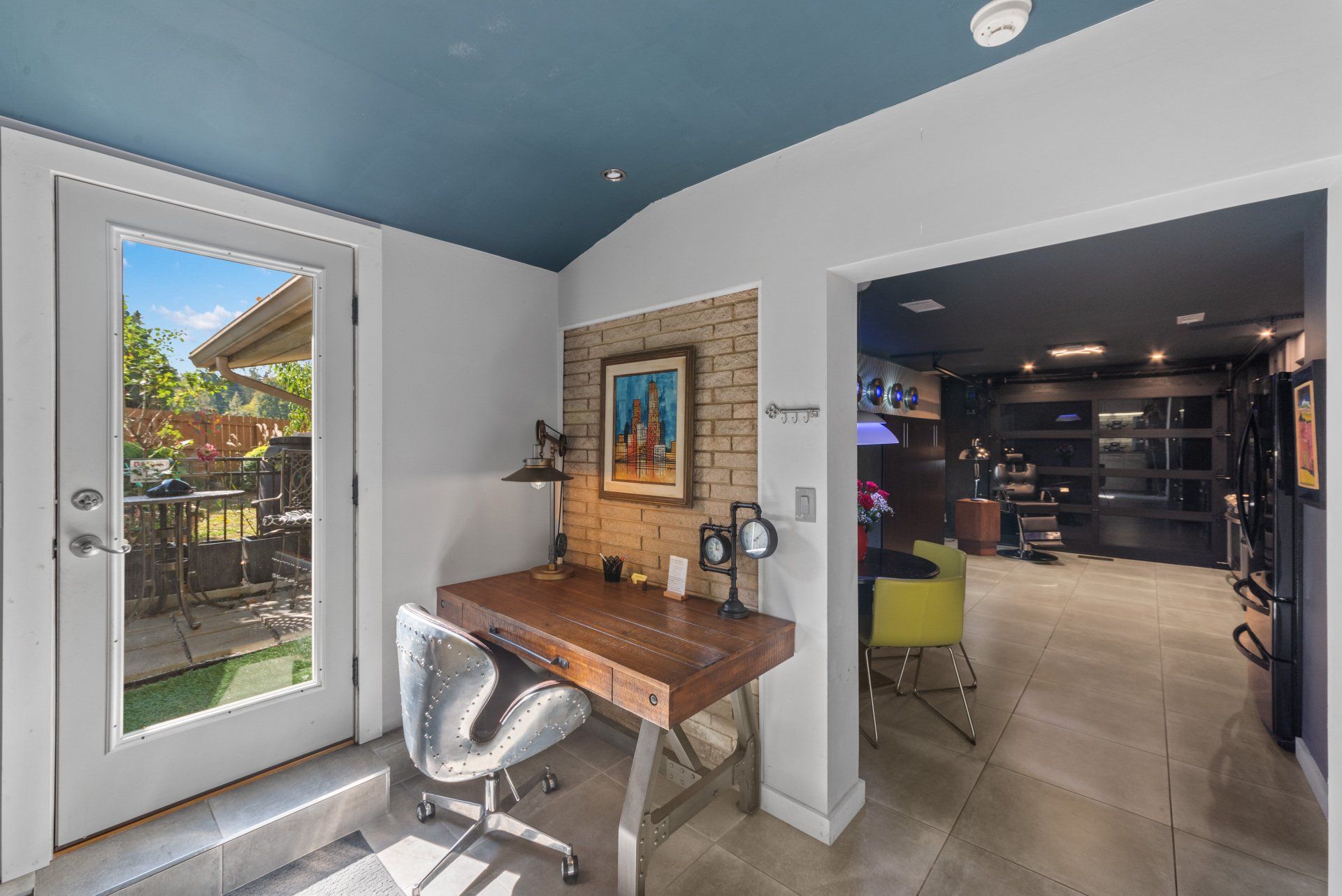 A home office with a desk and chair and a blue ceiling.