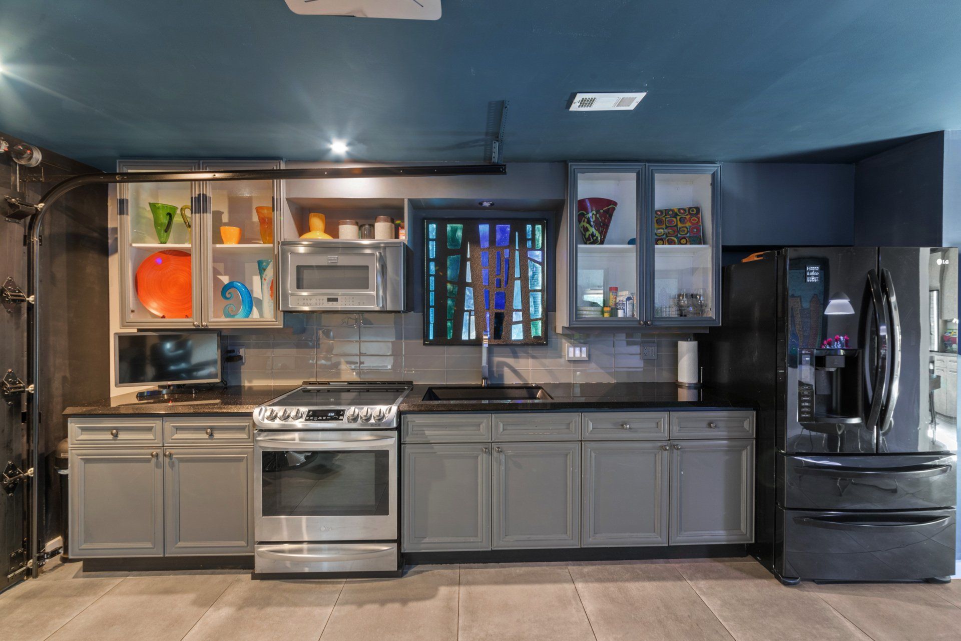 A kitchen with a stove , refrigerator , microwave and sink.
