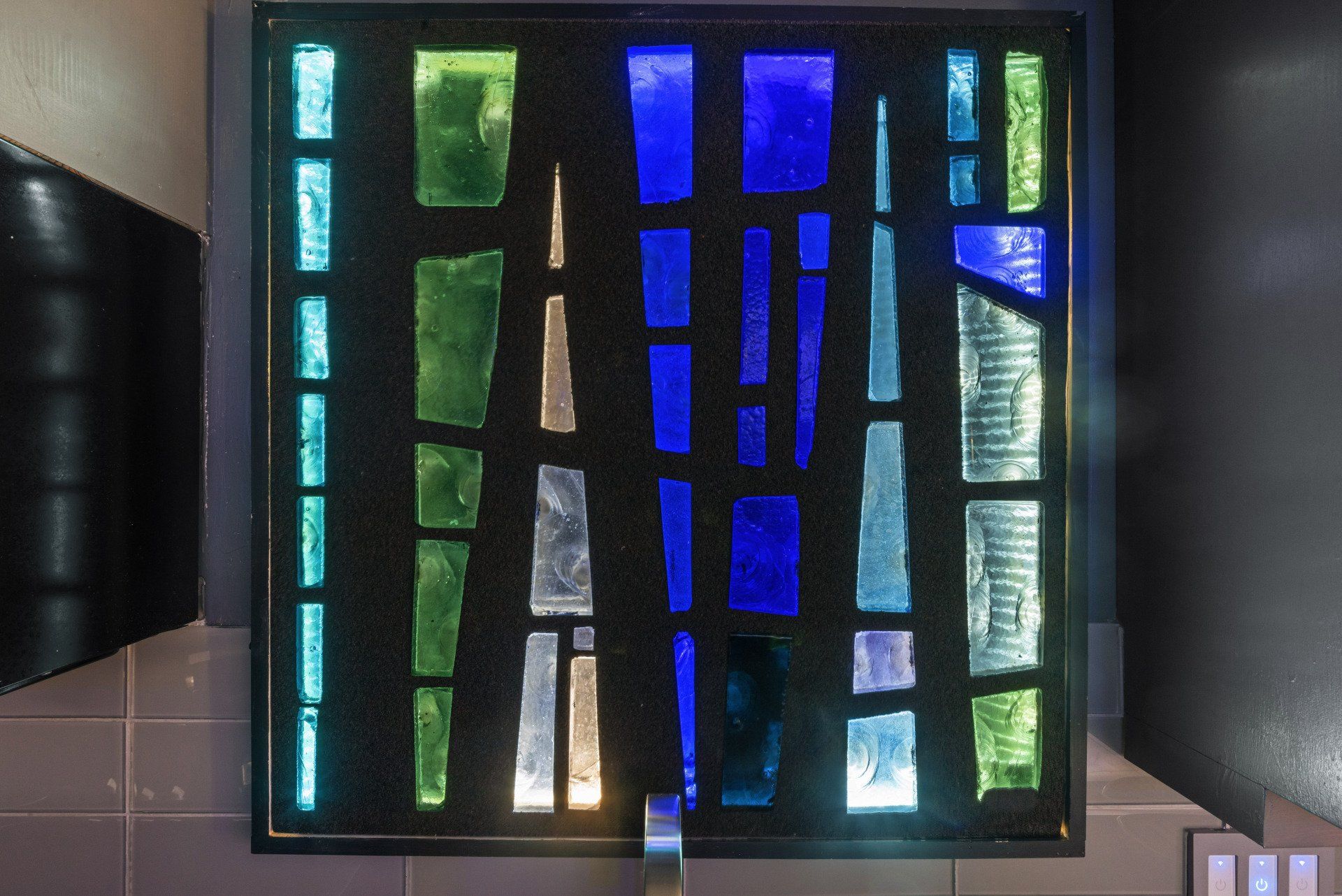 A stained glass window with blue green and white squares