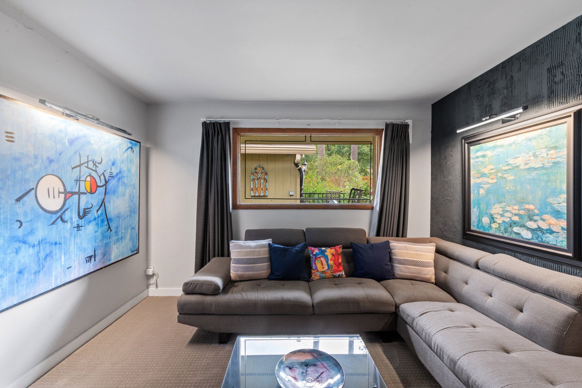 A living room with a couch , table , and paintings on the wall.