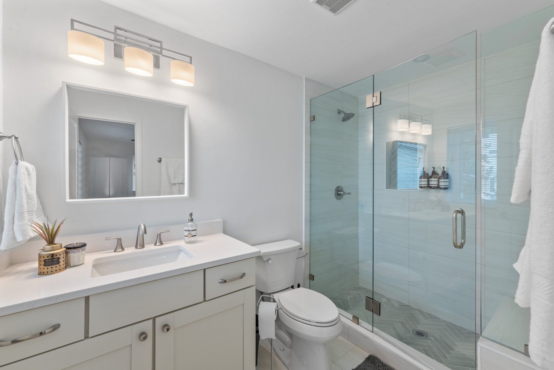 A bathroom with a toilet , sink , mirror and walk in shower.