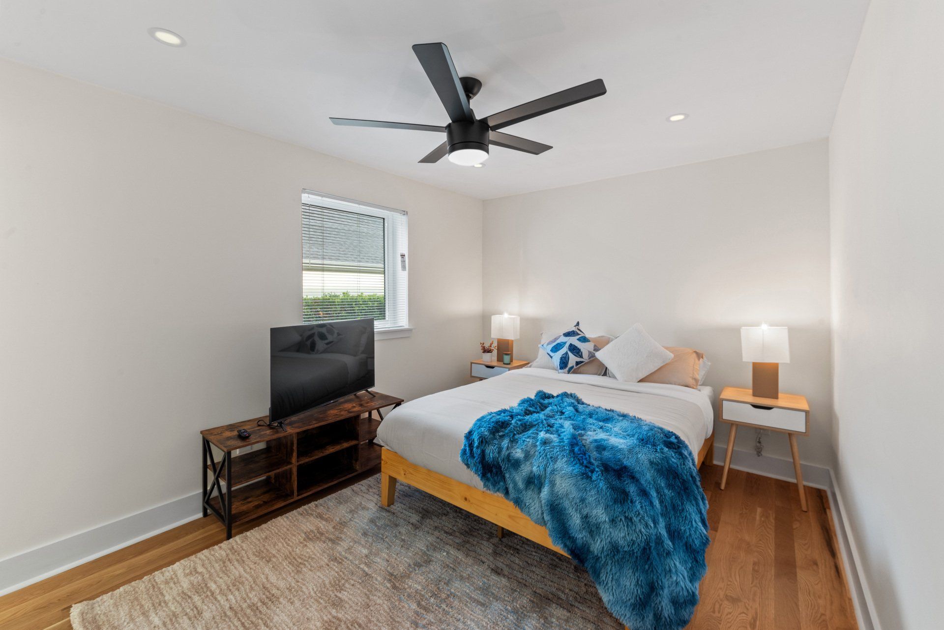 A bedroom with a bed , television , nightstand and ceiling fan.