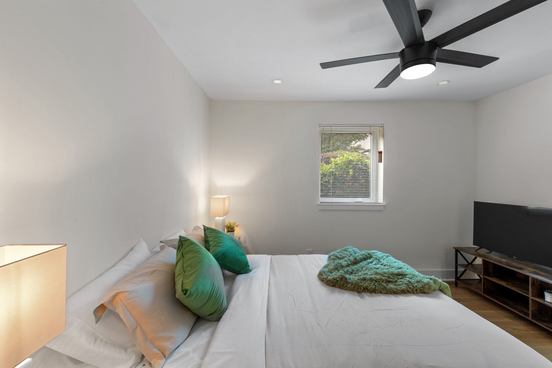 A bedroom with a large bed and a ceiling fan