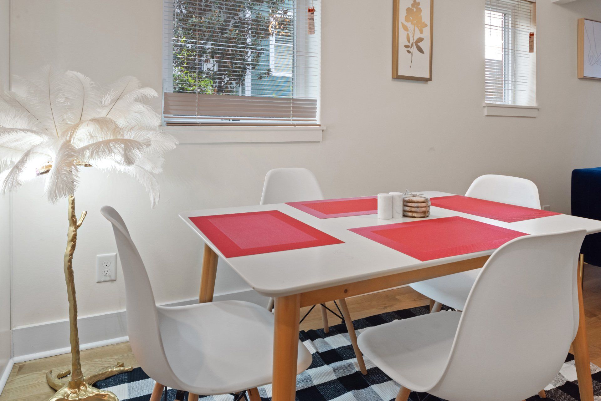 A dining room table with red place mats and white chairs