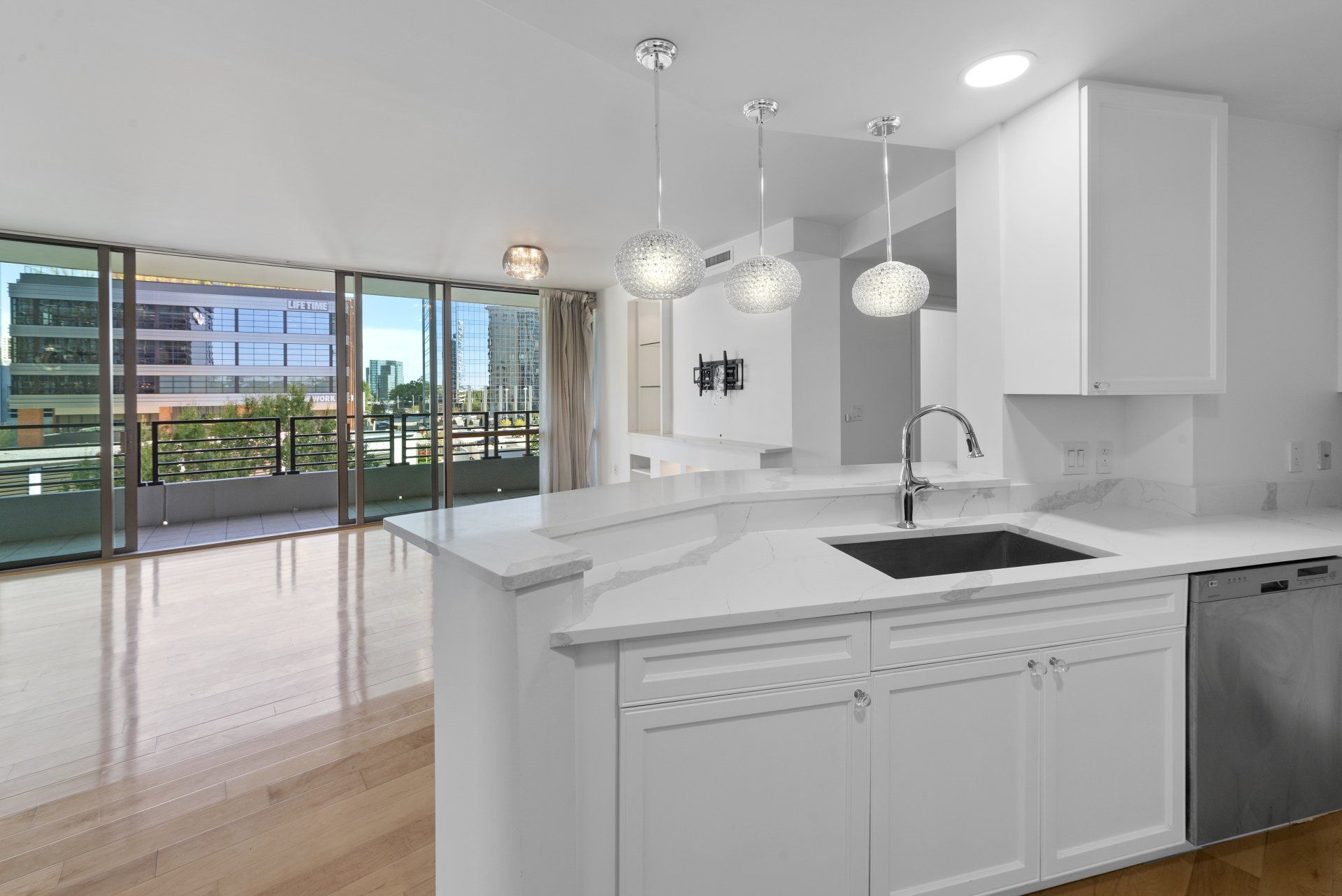An empty kitchen with white cabinets and a sink