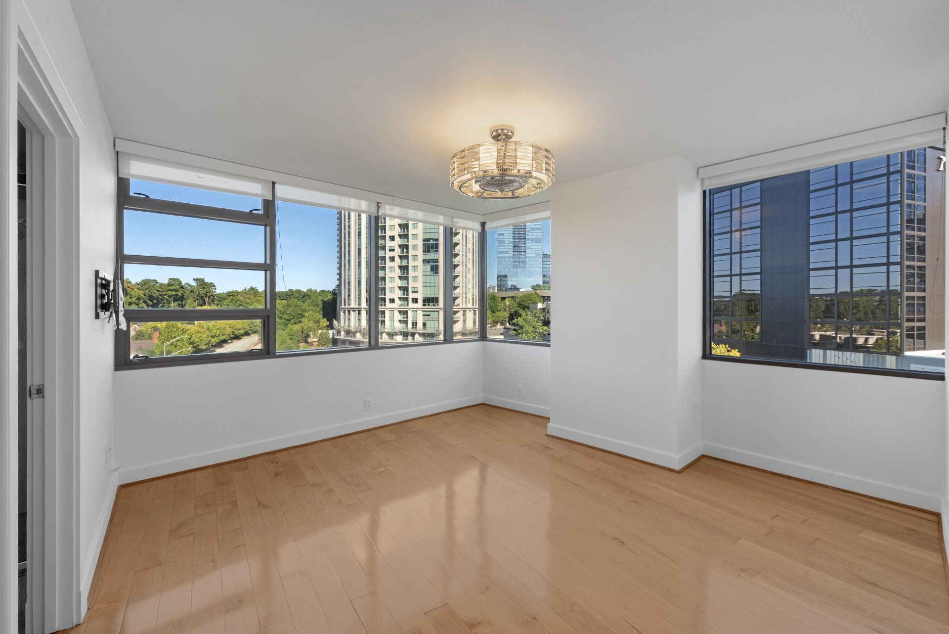 An empty living room with hardwood floors and lots of windows