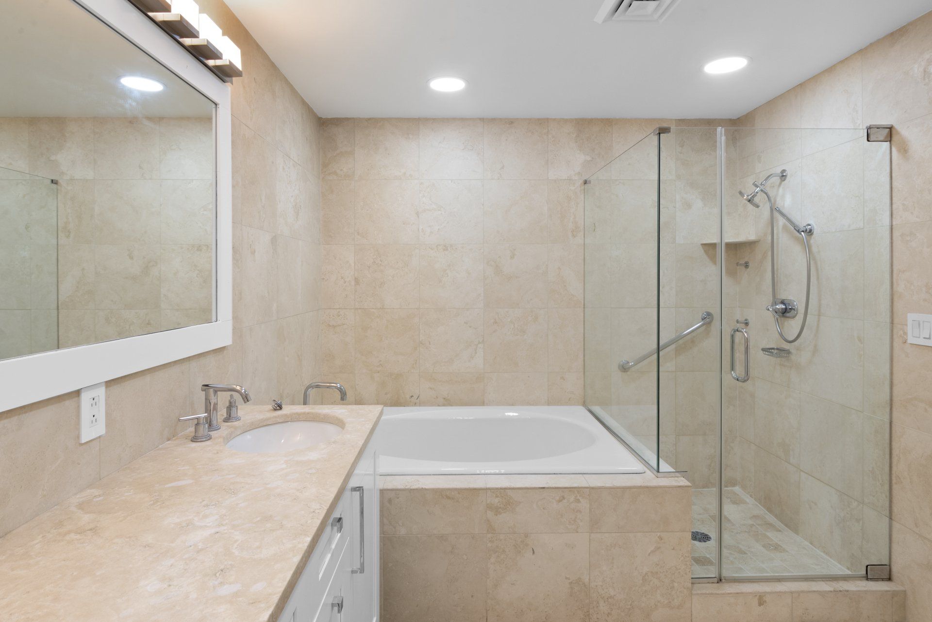 A bathroom with a tub , sink , mirror and shower