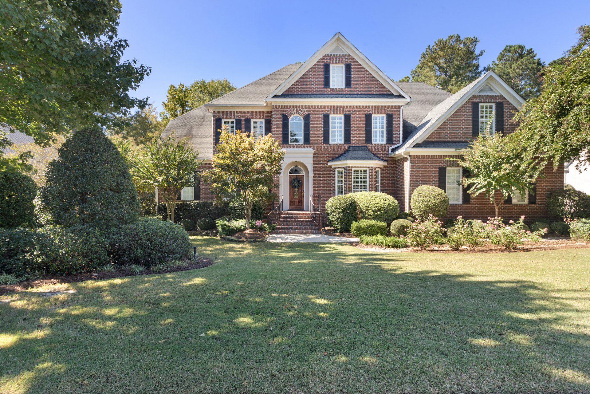 A large brick house with a large lawn in front of it