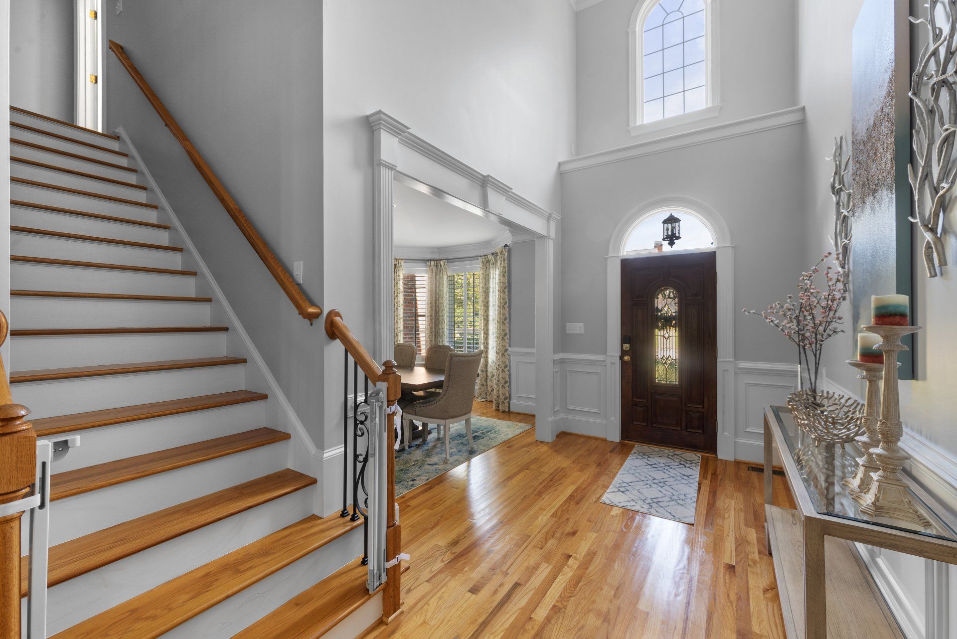 A hallway with hardwood floors and stairs leading up to the front door