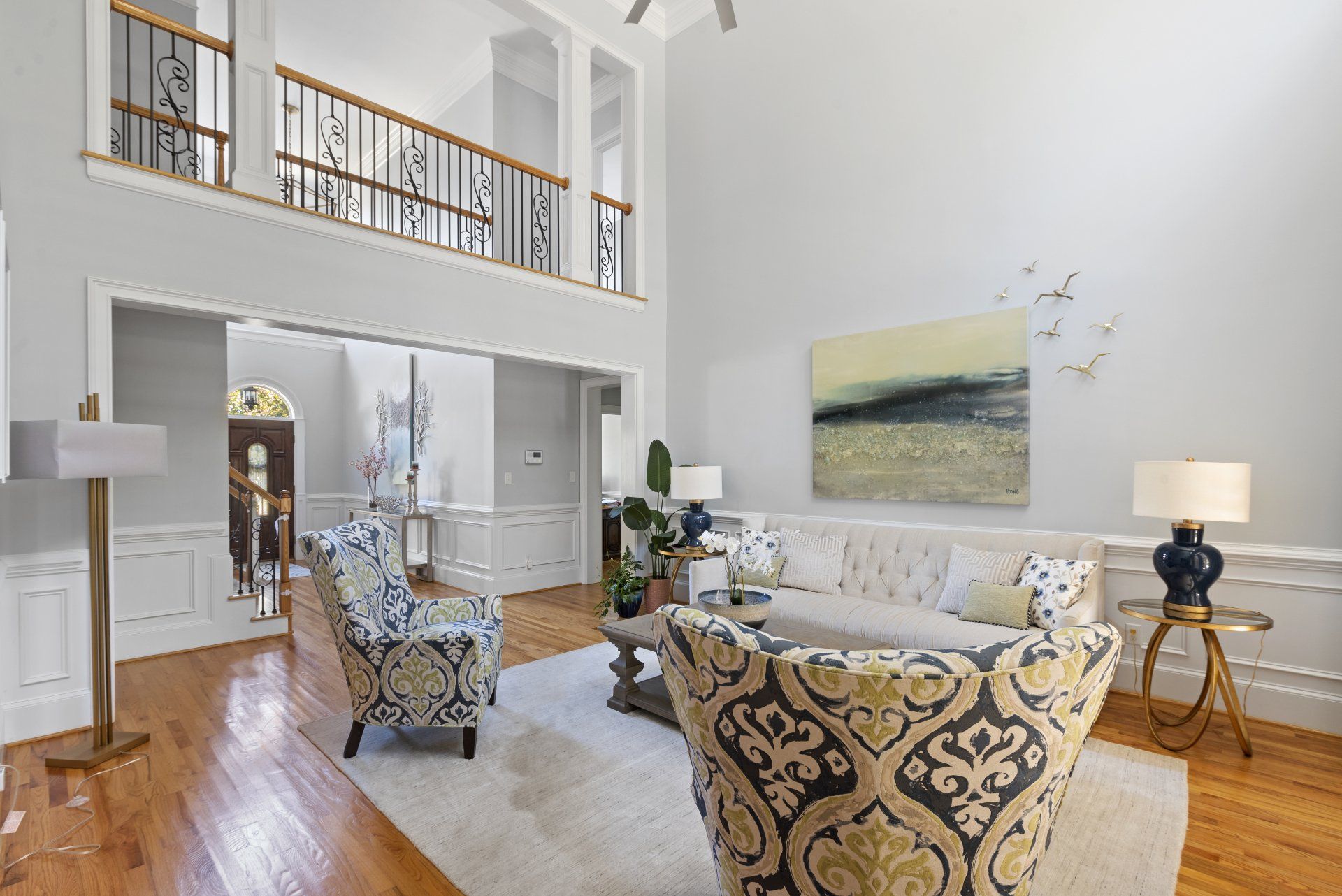 A living room with a couch , chairs , and a painting on the wall.