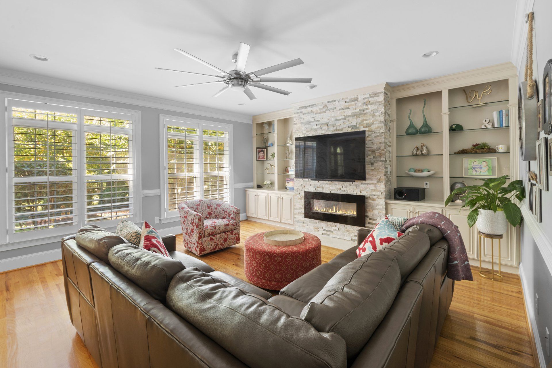 A living room with a couch , fireplace , television and ceiling fan.