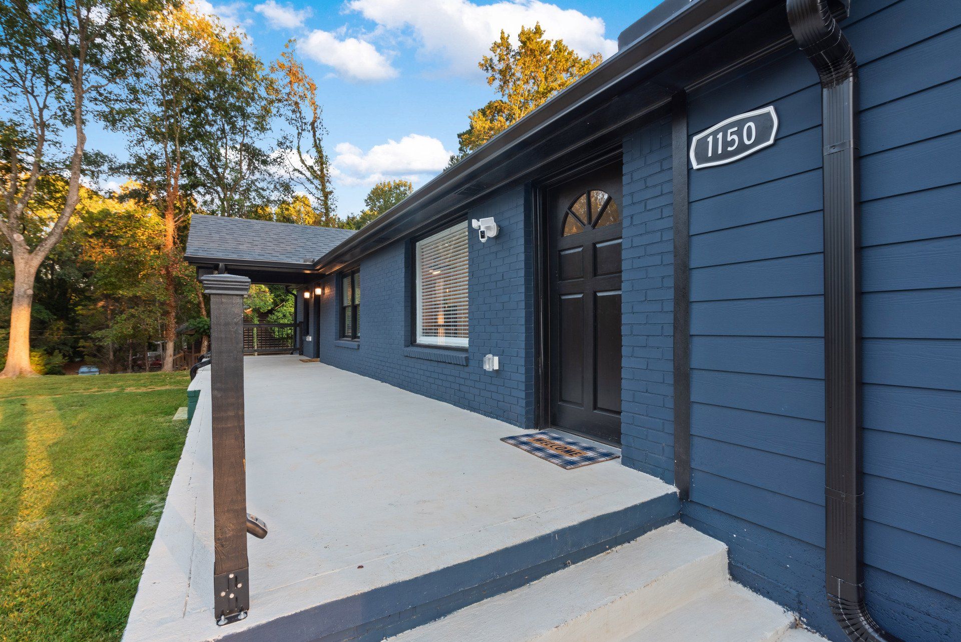 A blue house with a black door and a porch.