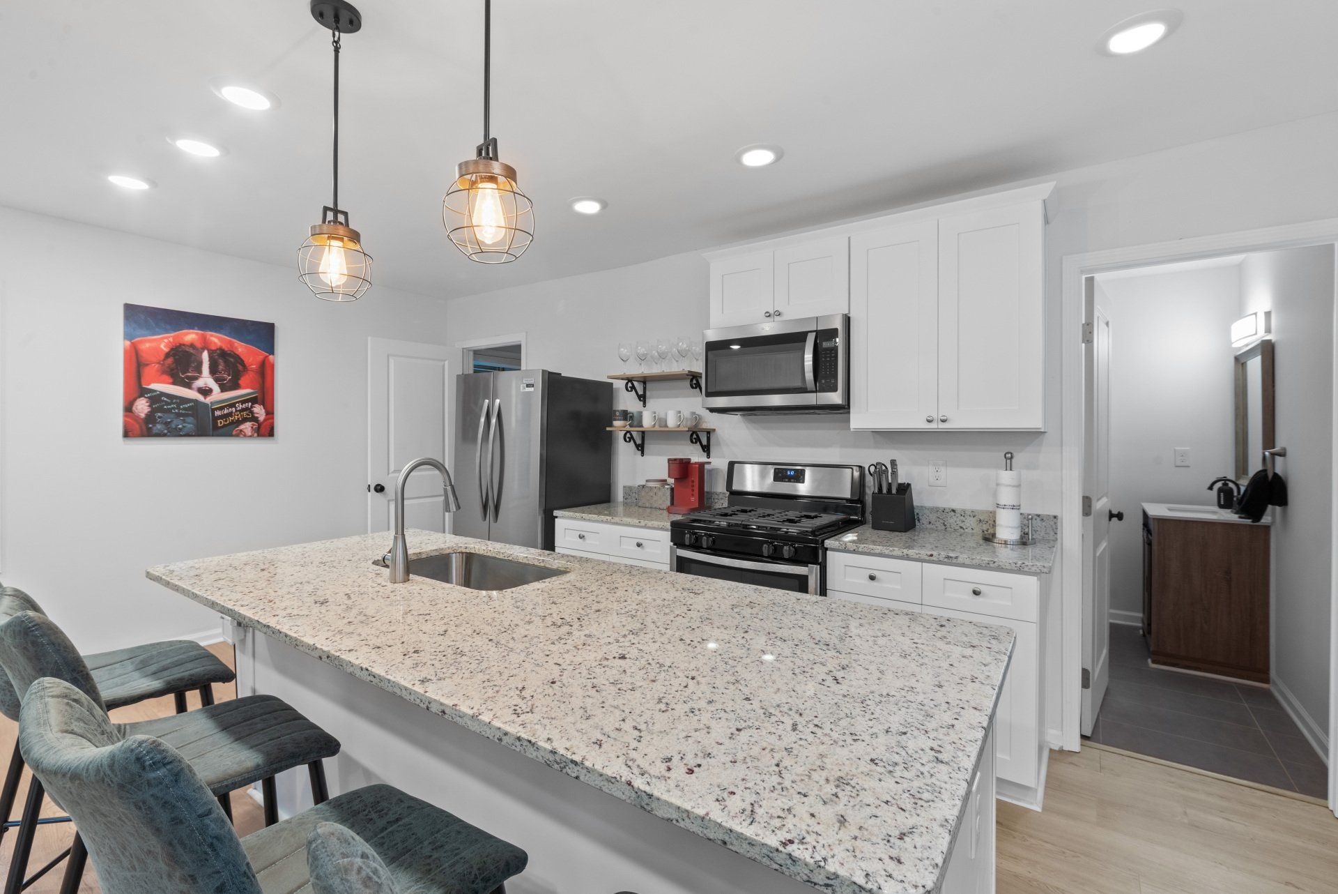 A kitchen with white cabinets , granite counter tops , stainless steel appliances and a large island.