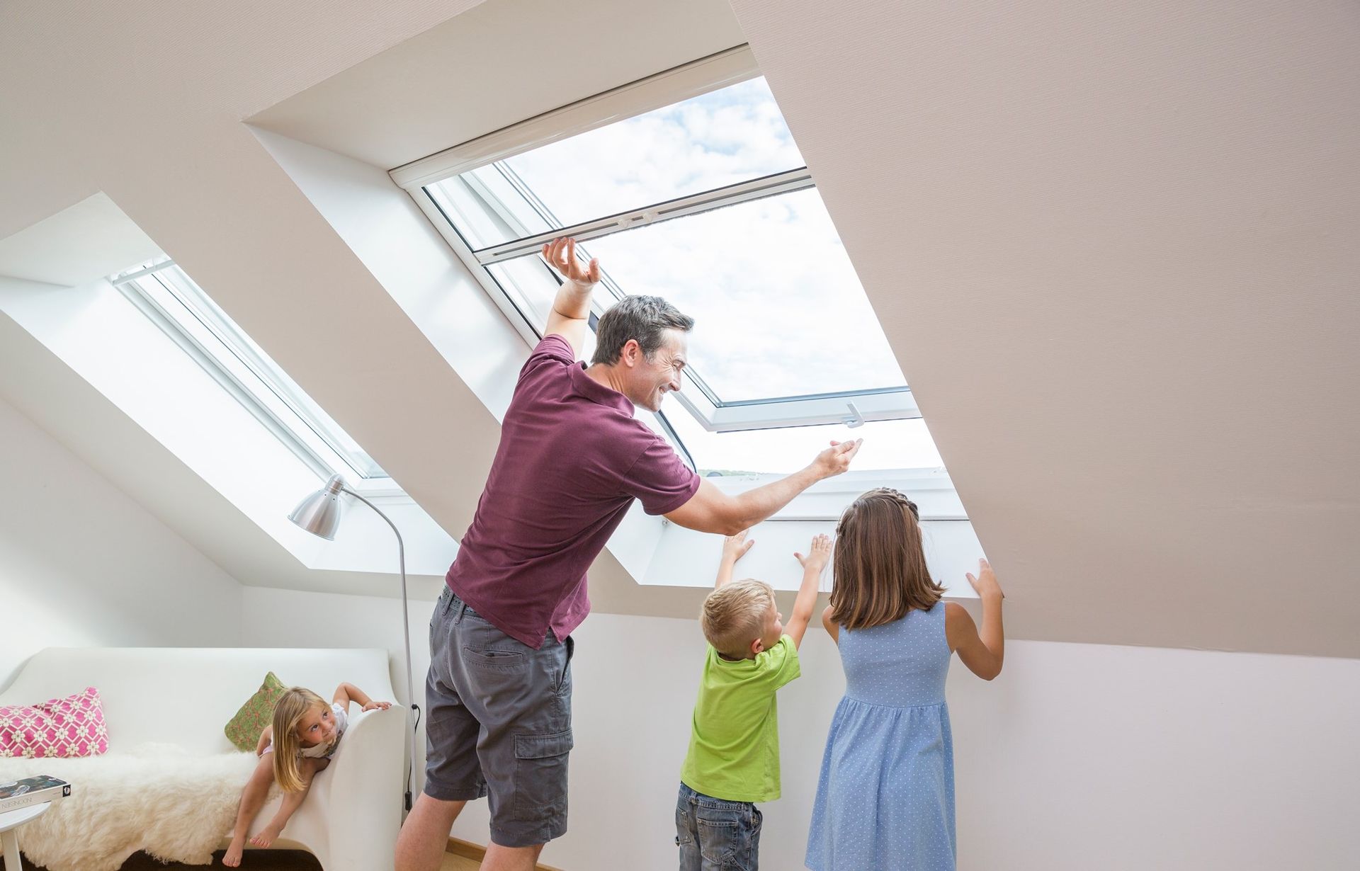 Une famille regarde par la fenêtre du grenier ; le père l'ouvre tandis que les enfants se penchent vers elle.