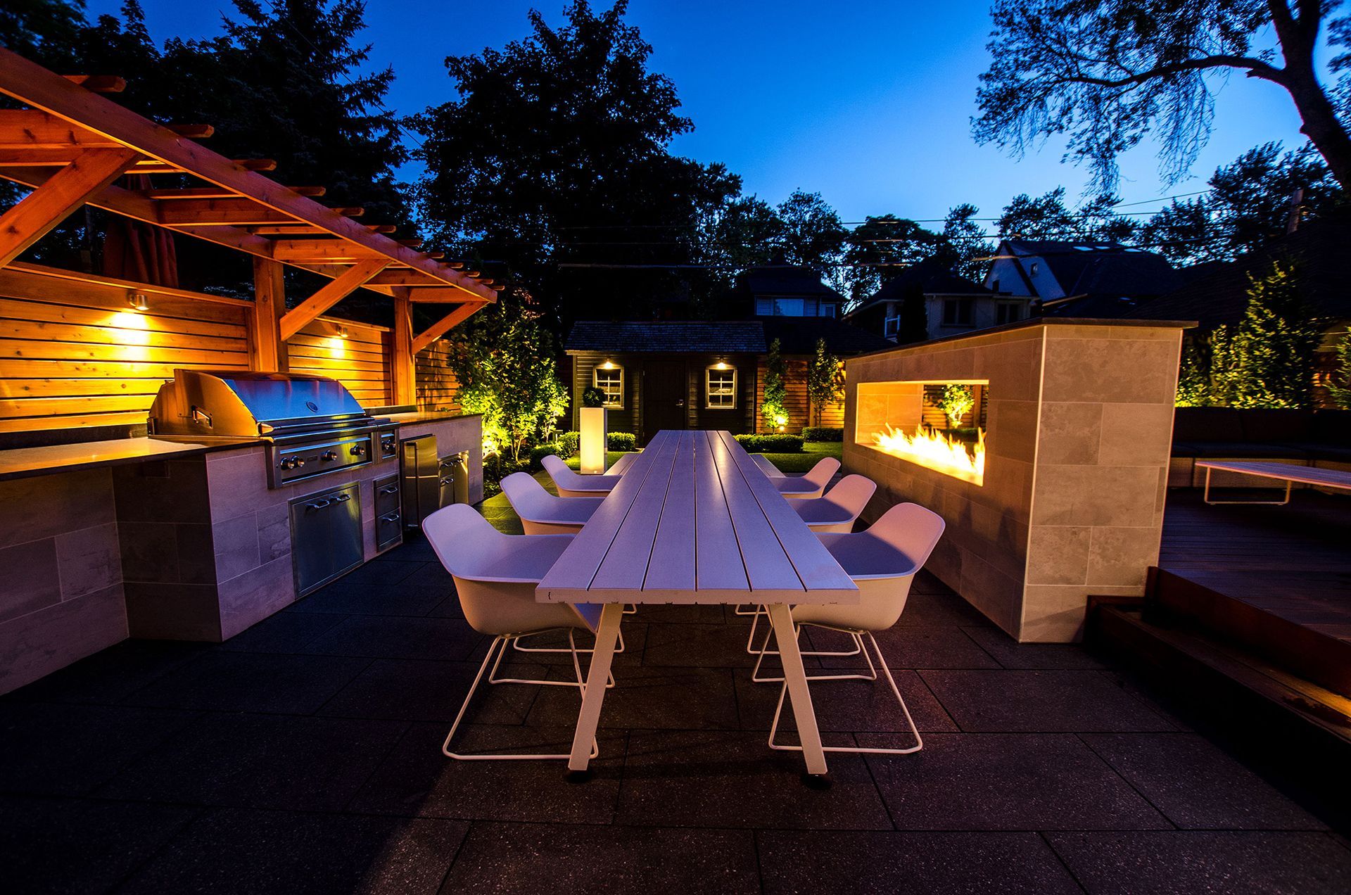 A patio area with a long table and chairs at night