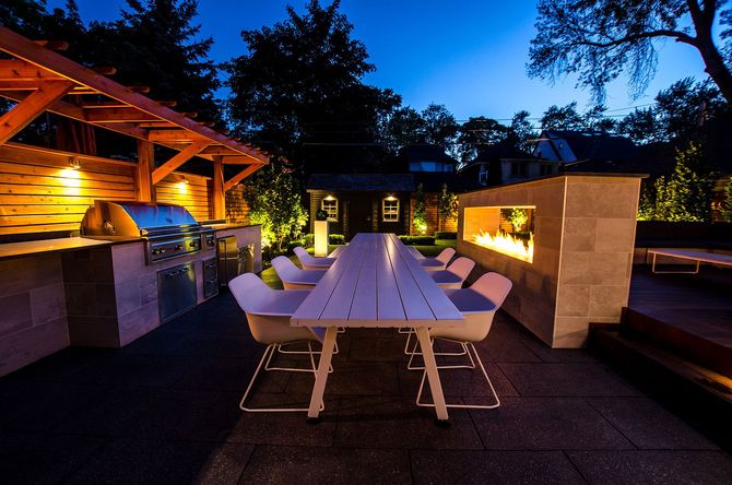 A patio area with a long table and chairs at night