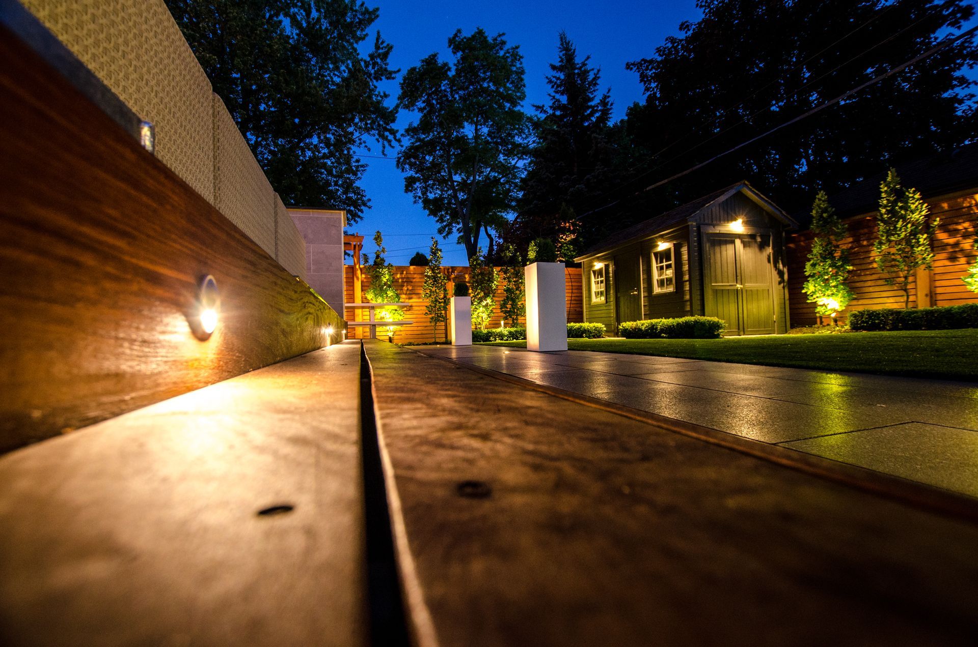A wooden walkway with a shed in the background at night