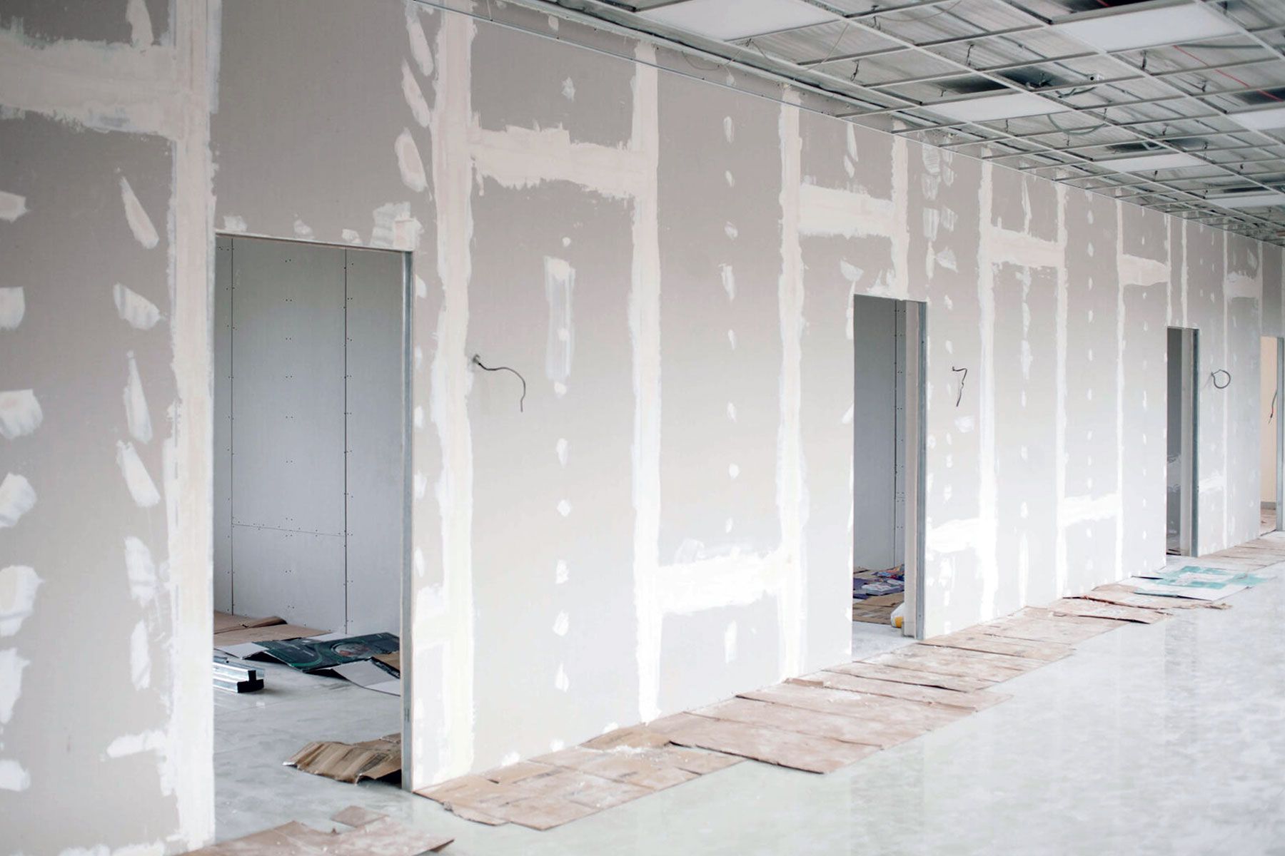 An unfinished office interior featuring drywall partitions with taped seams and open doorways.