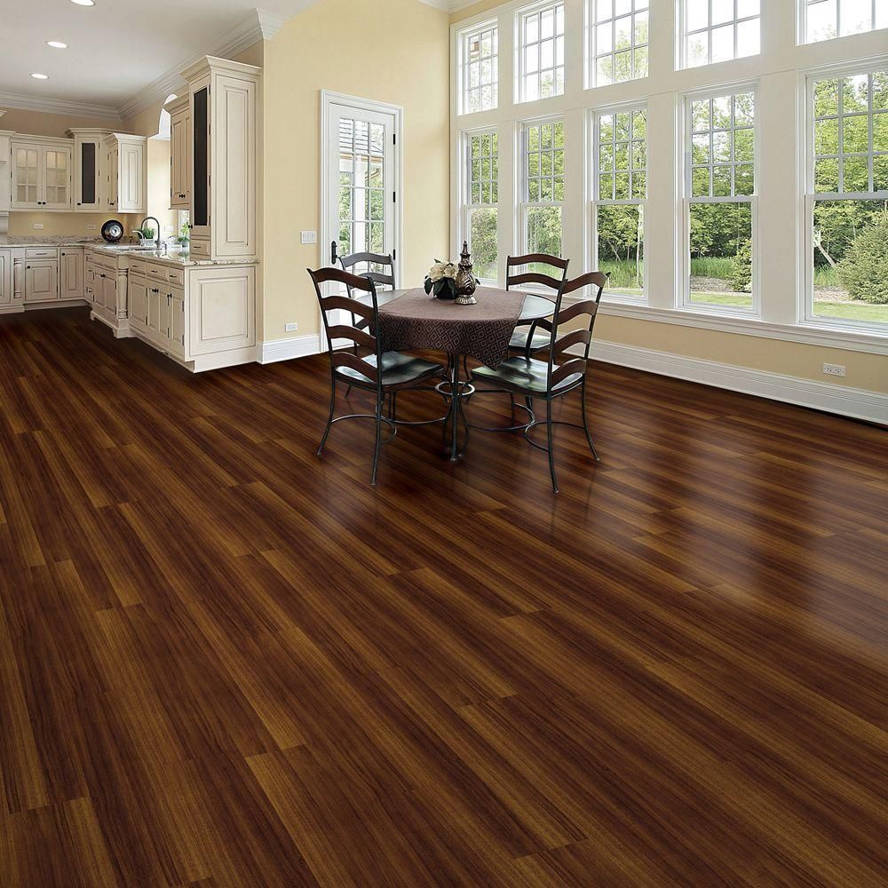A bright kitchen and dining area featuring dark wood plank flooring, white cabinets, and a dining set by a row of windows.