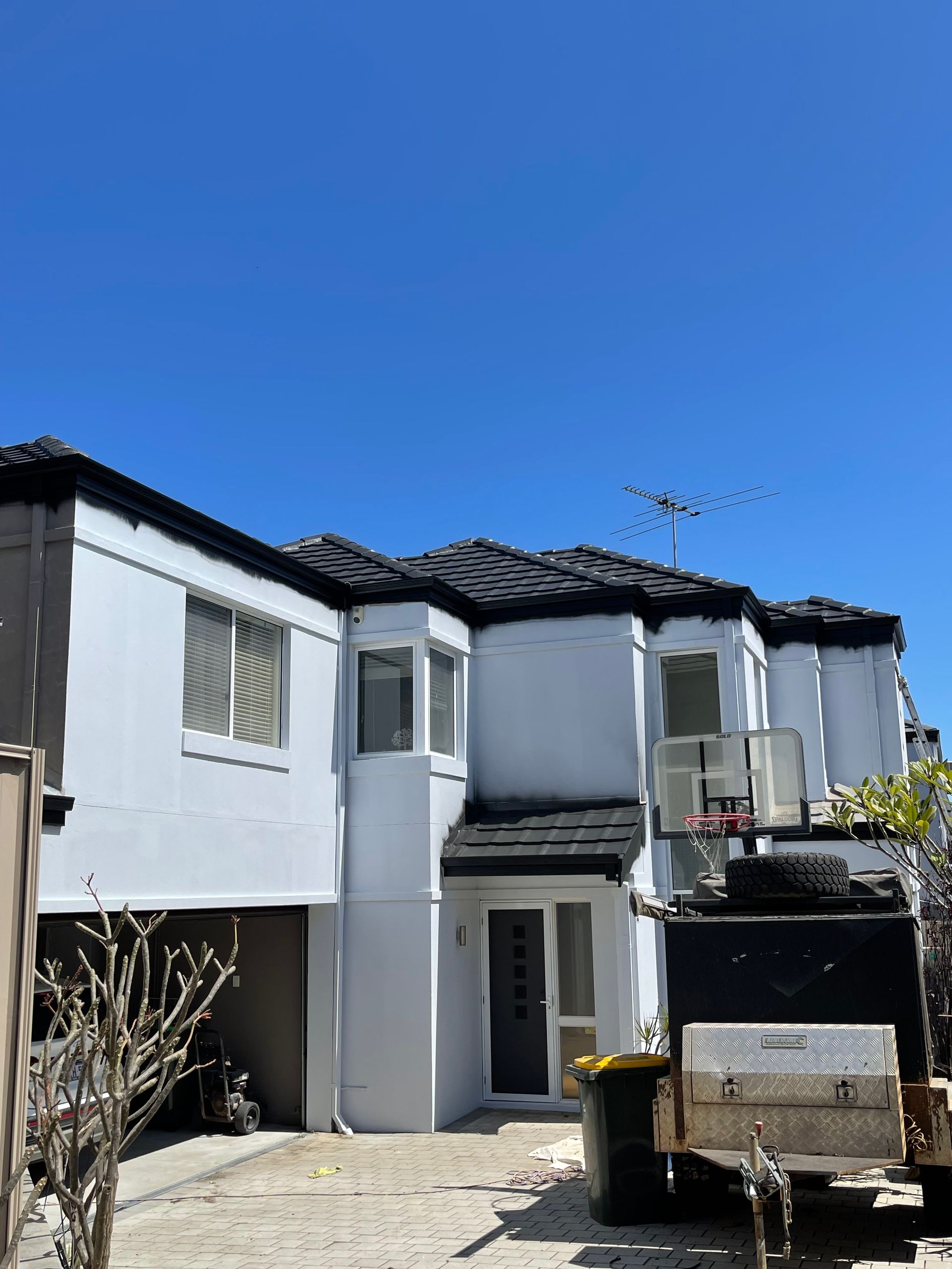 A white house with a black roof and a truck parked in front of it.