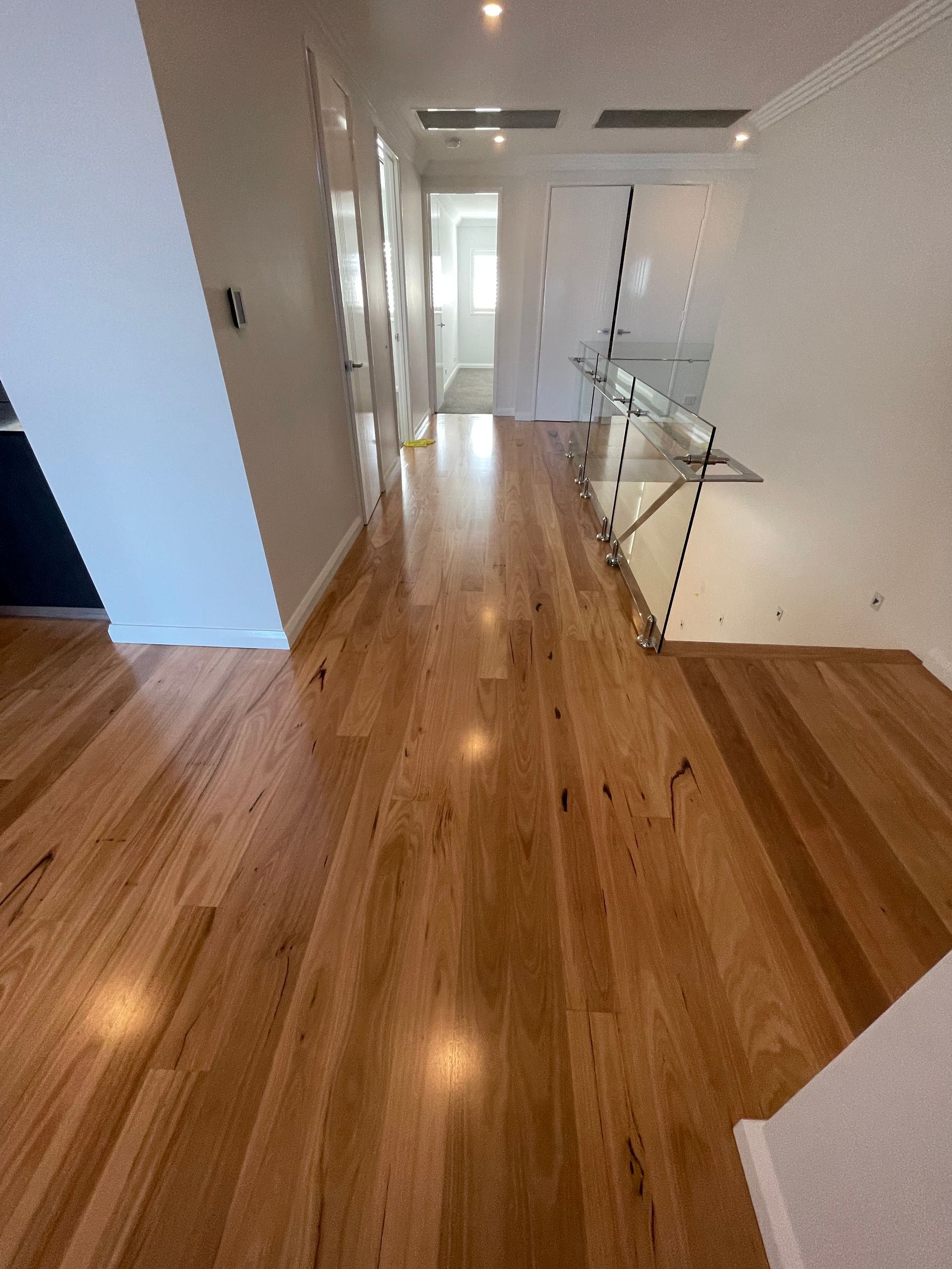 A hallway with hardwood floors and stairs in a house.