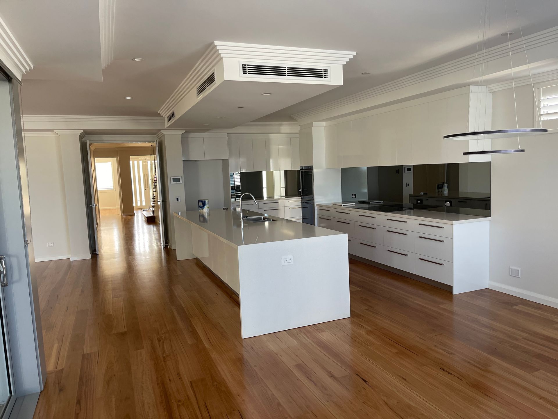 An empty kitchen with white cabinets and hardwood floors