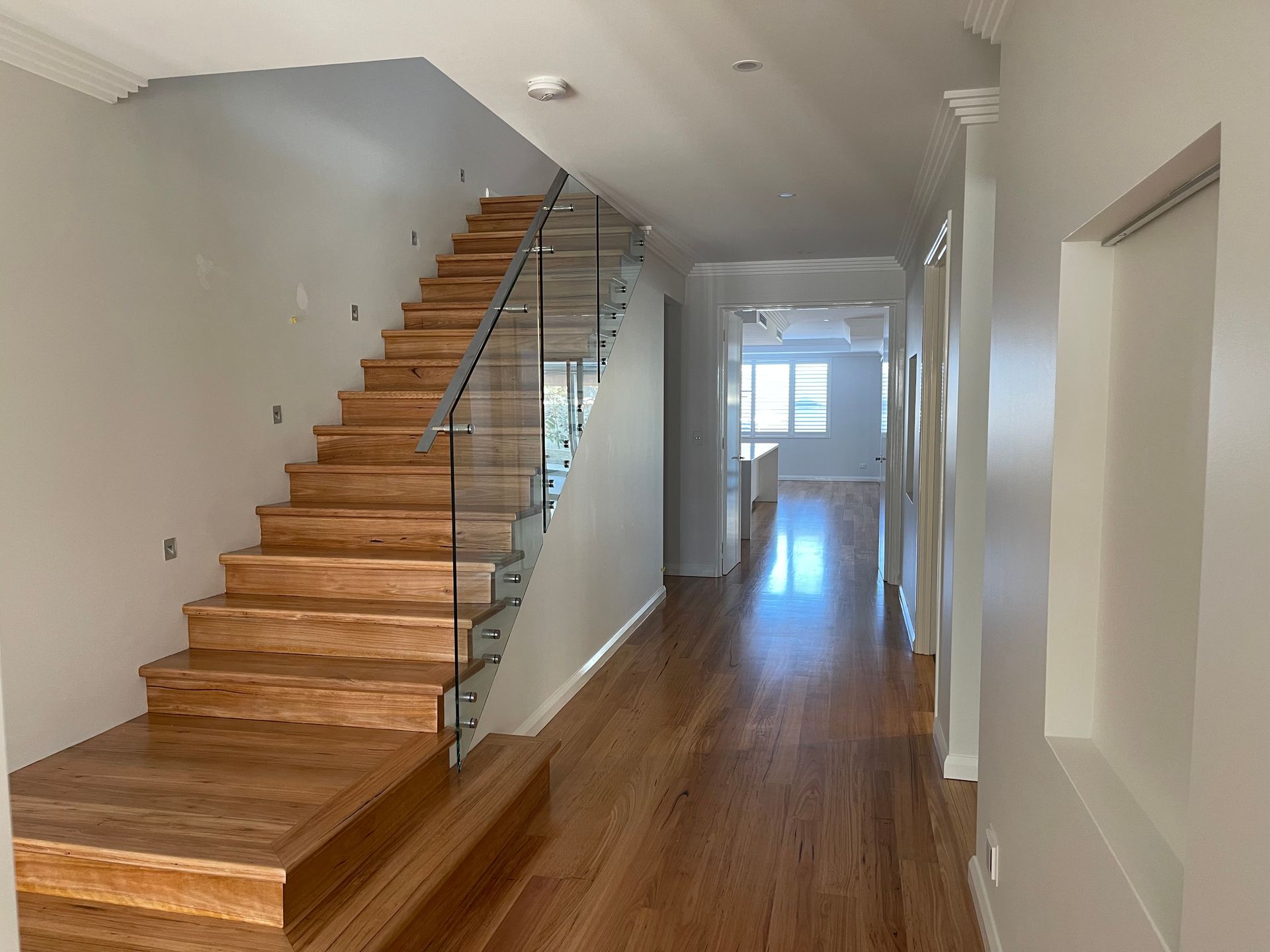 A hallway with wooden stairs and a glass railing