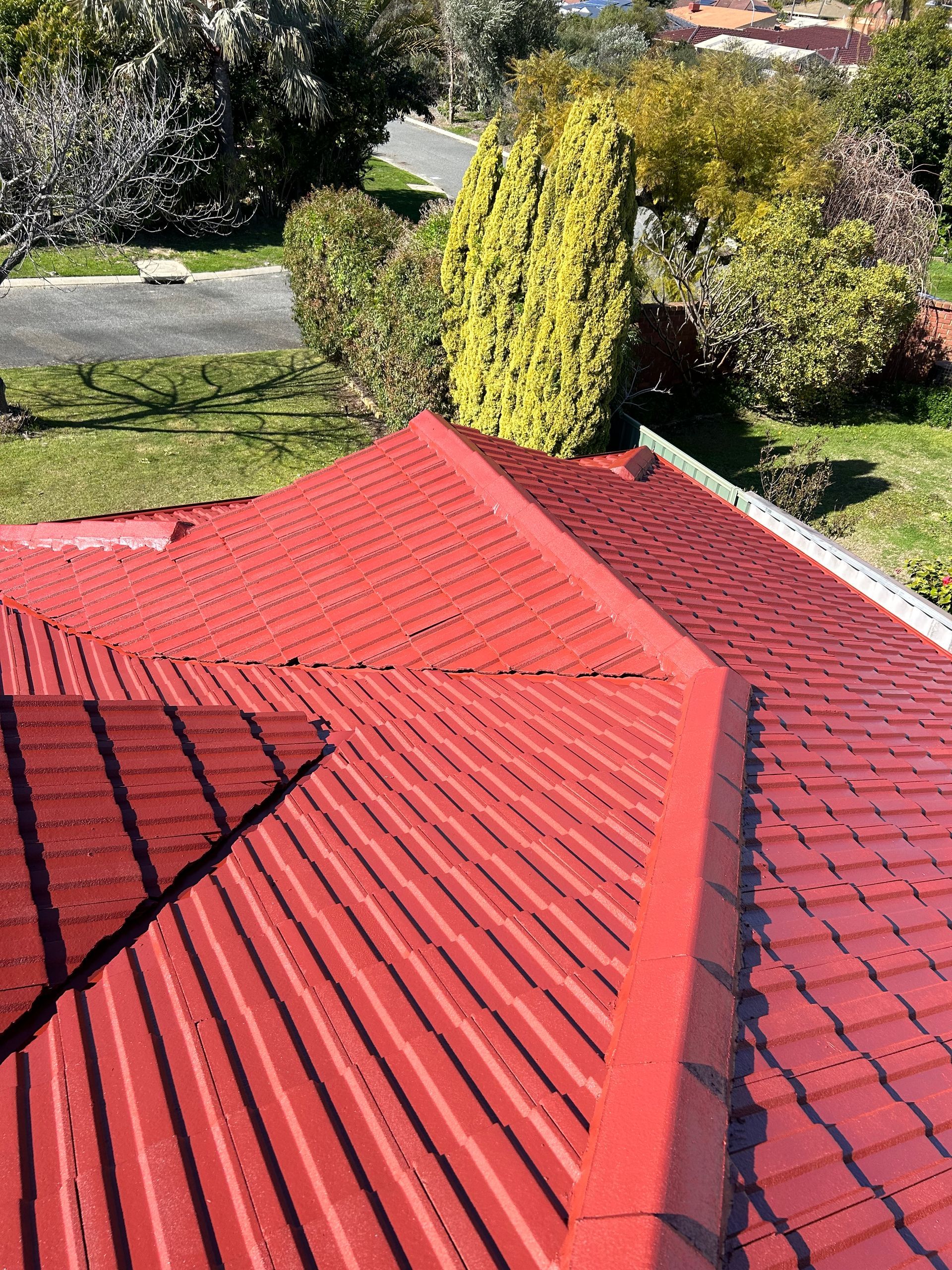 A red roof of a house with trees in the background.