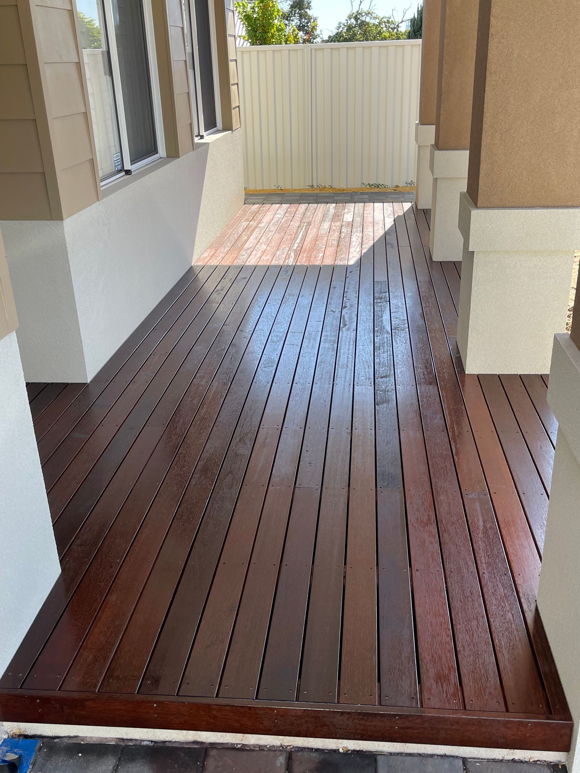 A wooden deck is sitting in front of a house.