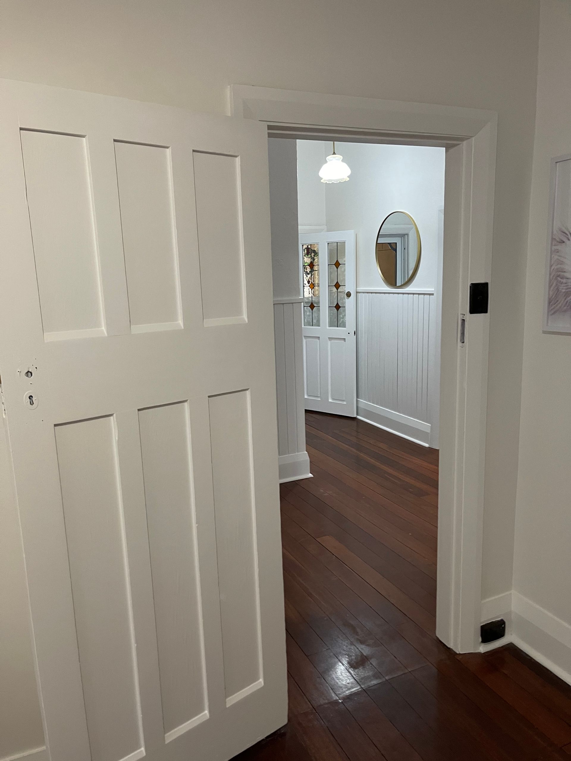 A white door is open to a hallway with hardwood floors.