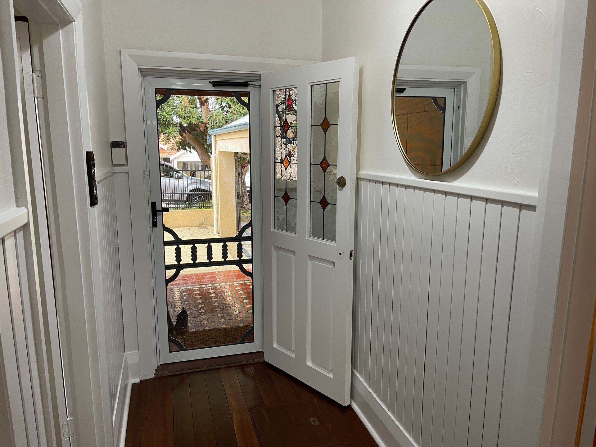 A hallway with a door open and a mirror on the wall.