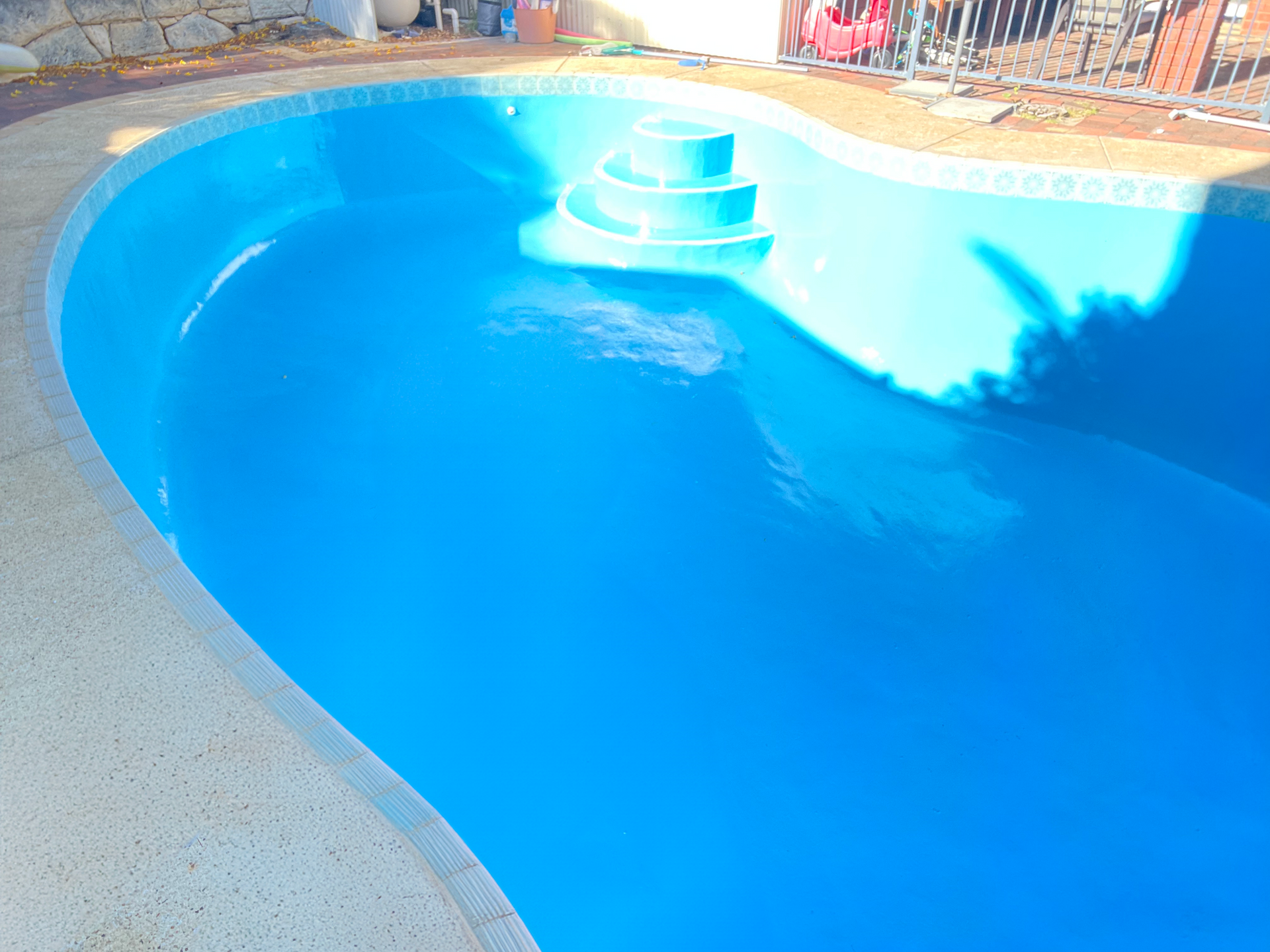 A large blue swimming pool with stairs in it