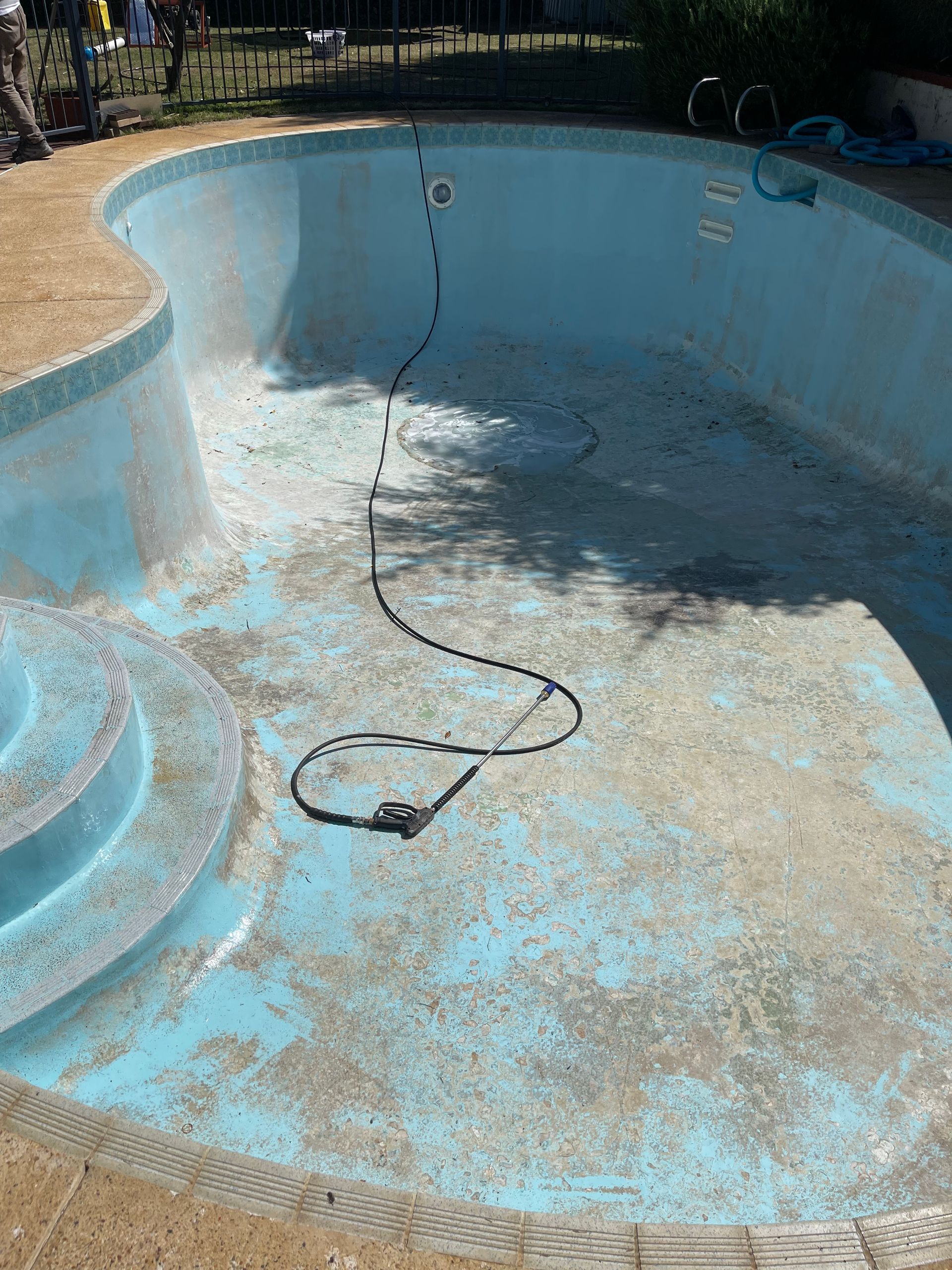 An empty swimming pool with a hose coming out of it