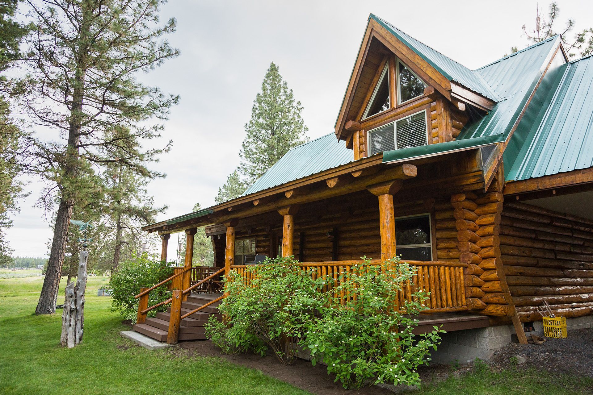 A log cabin with a green roof and a large porch