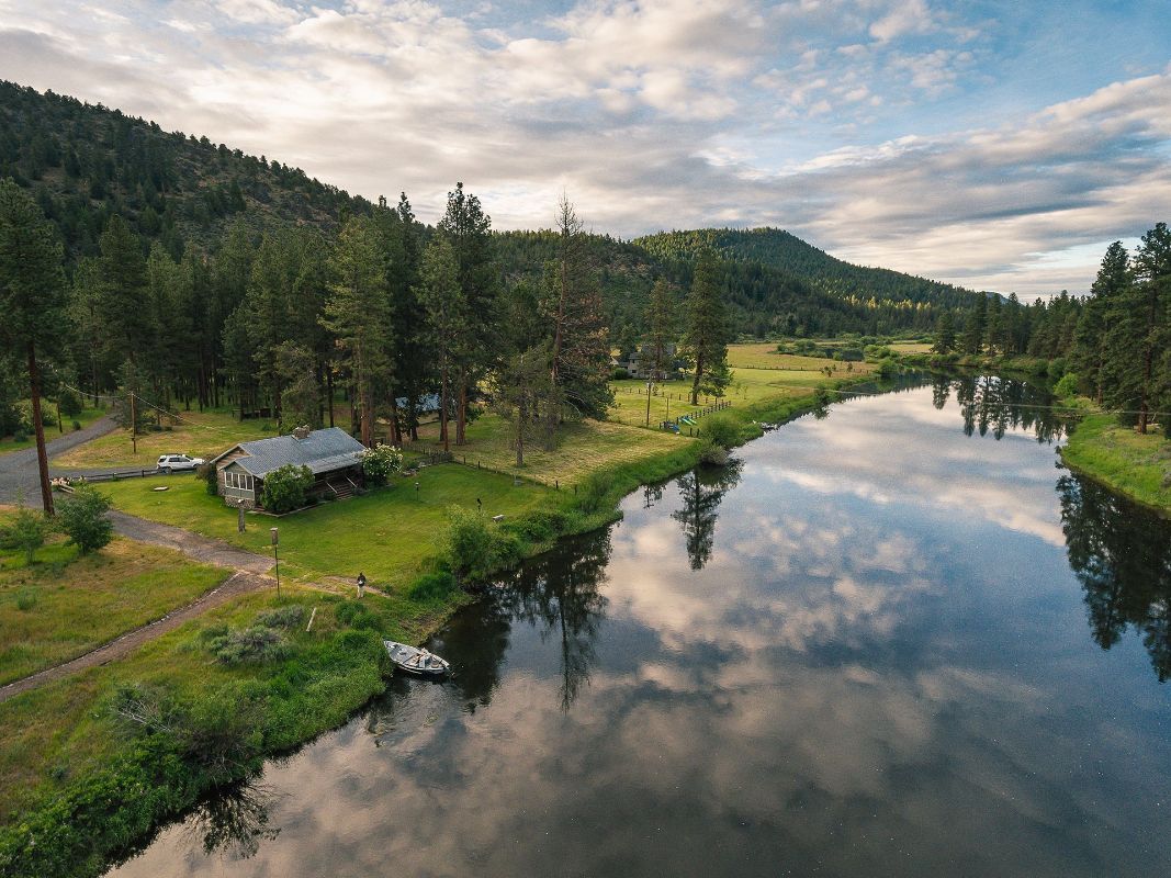 An aerial view of a river surrounded by trees and a house.