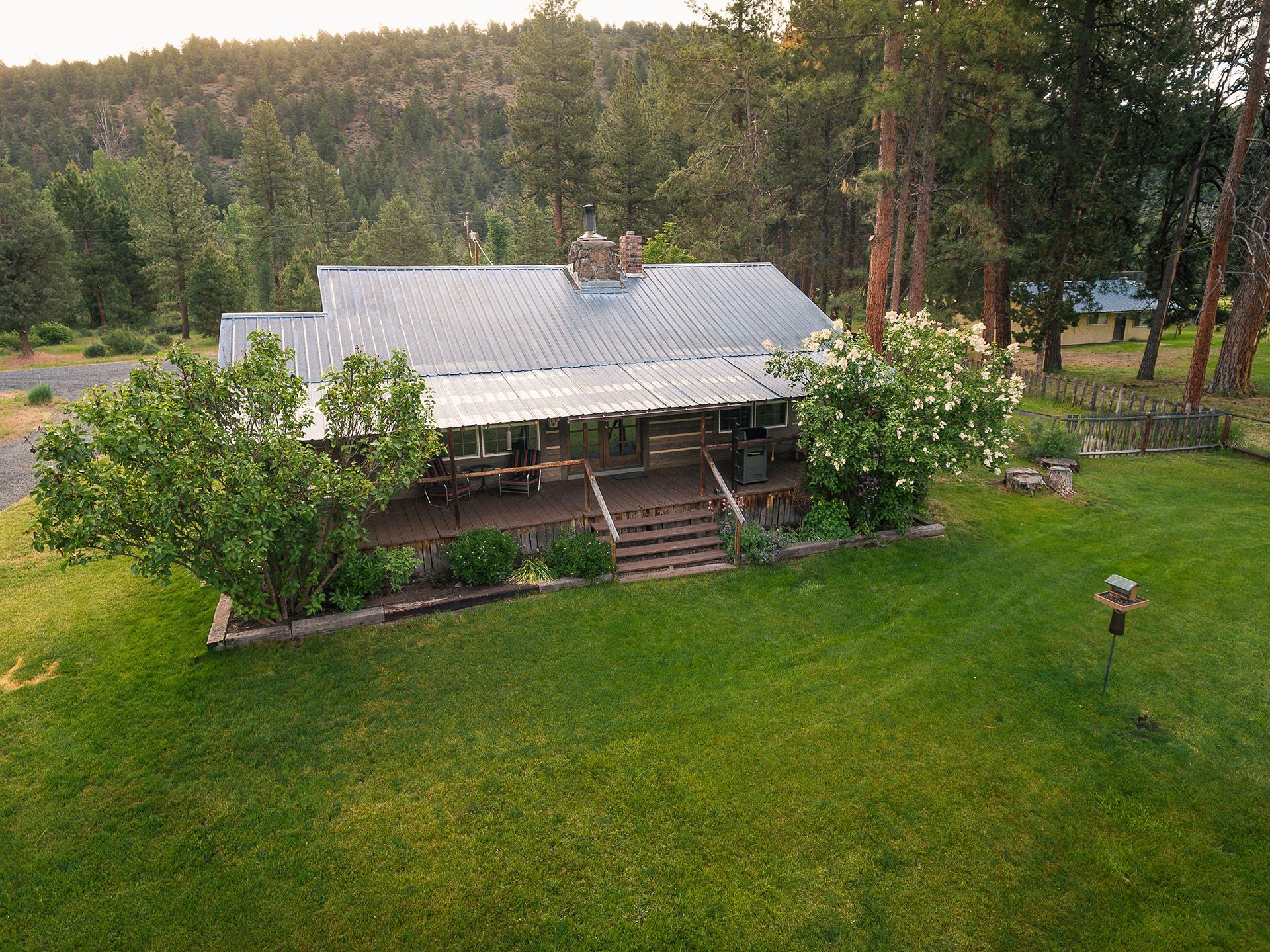 An aerial view of a house in the middle of a lush green field surrounded by trees.