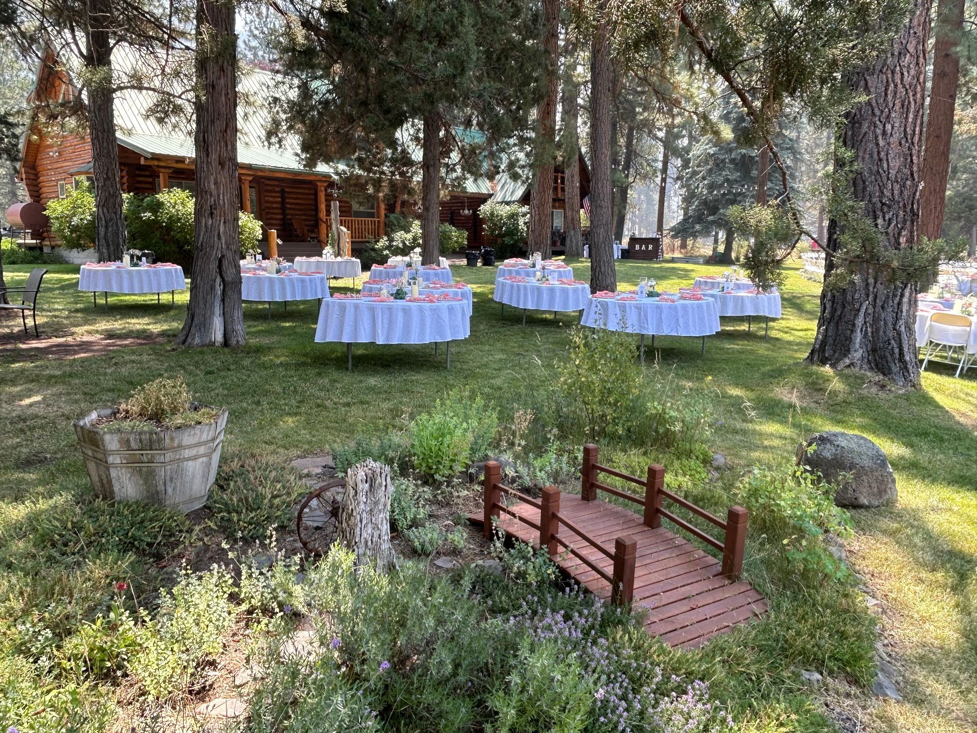 A wooden bridge in the middle of a forest with tables set up for a wedding reception.